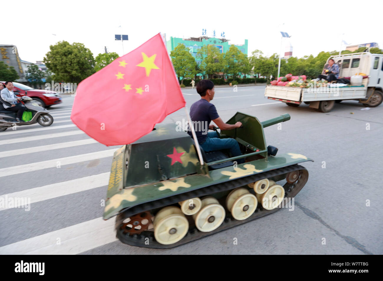 Un uomo cinese aziona un giocattolo in miniatura serbatoio su una strada di Xiangyang city, centrale cinese della provincia di Hubei, 28 aprile 2017. Un uomo cinese ha guidato una miniat Foto Stock