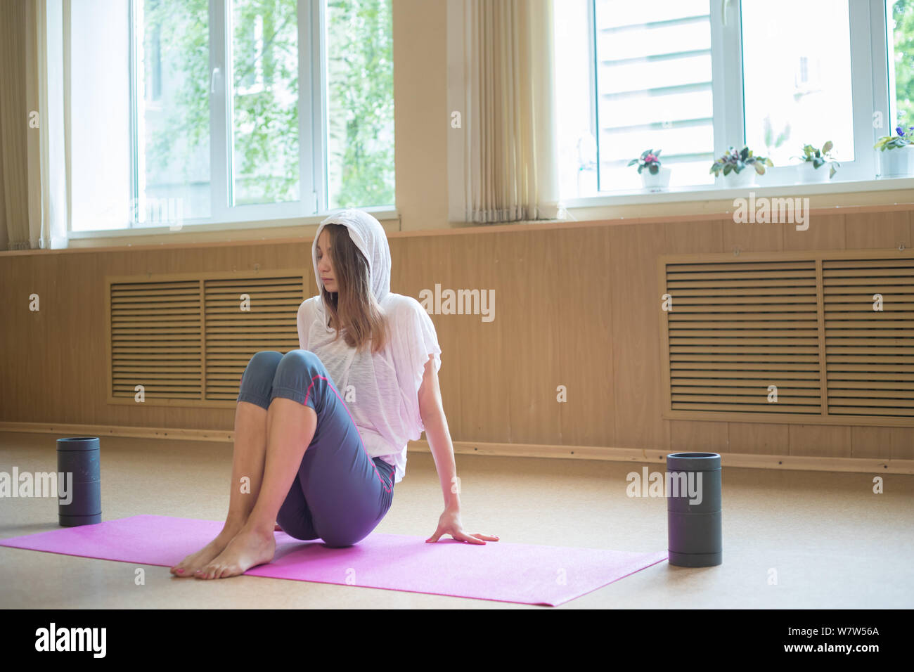 Slim giovane donna seduta sul materassino yoga in studio di danza Foto Stock