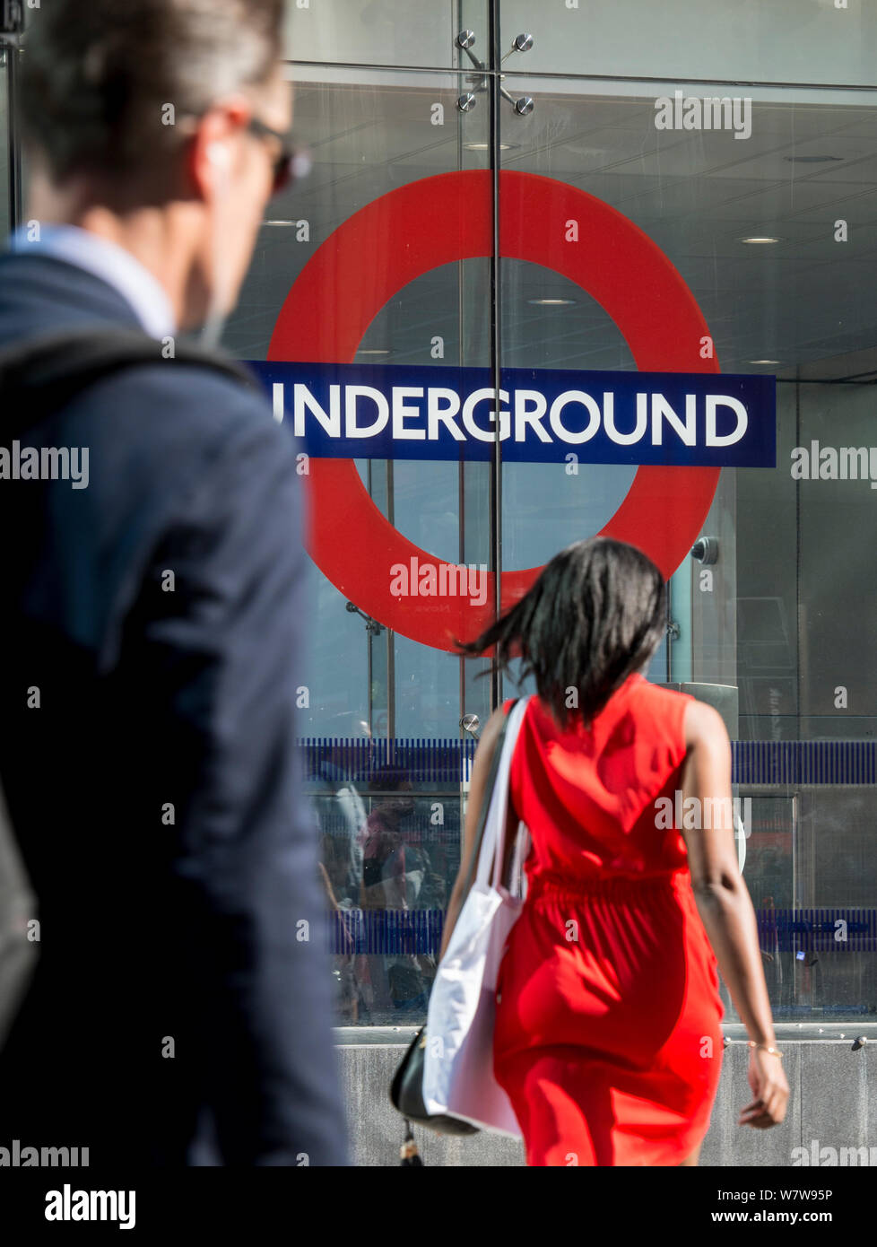 Un uomo e una donna sulla loro mattina commutare all'ingresso per la stazione della metropolitana di Victoria, Londra Centrale. Foto Stock