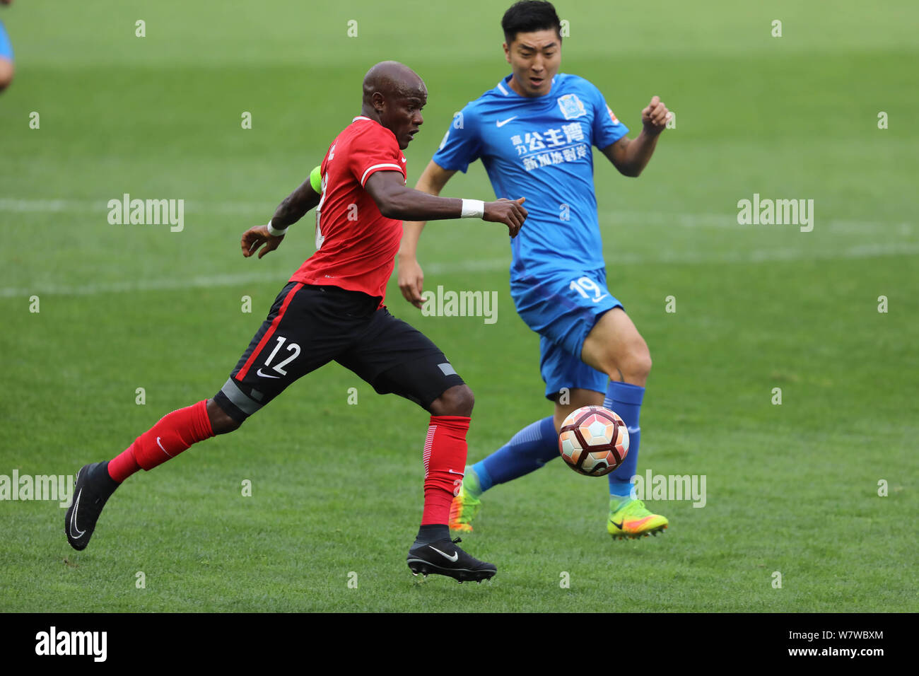 Zambia giocatore di calcio James Chamanga di Liaoning Whowin, sinistra, sfide con Jiang Jihong di Guangzhou R&F nel loro quinto round corrispondere durante il 2 Foto Stock