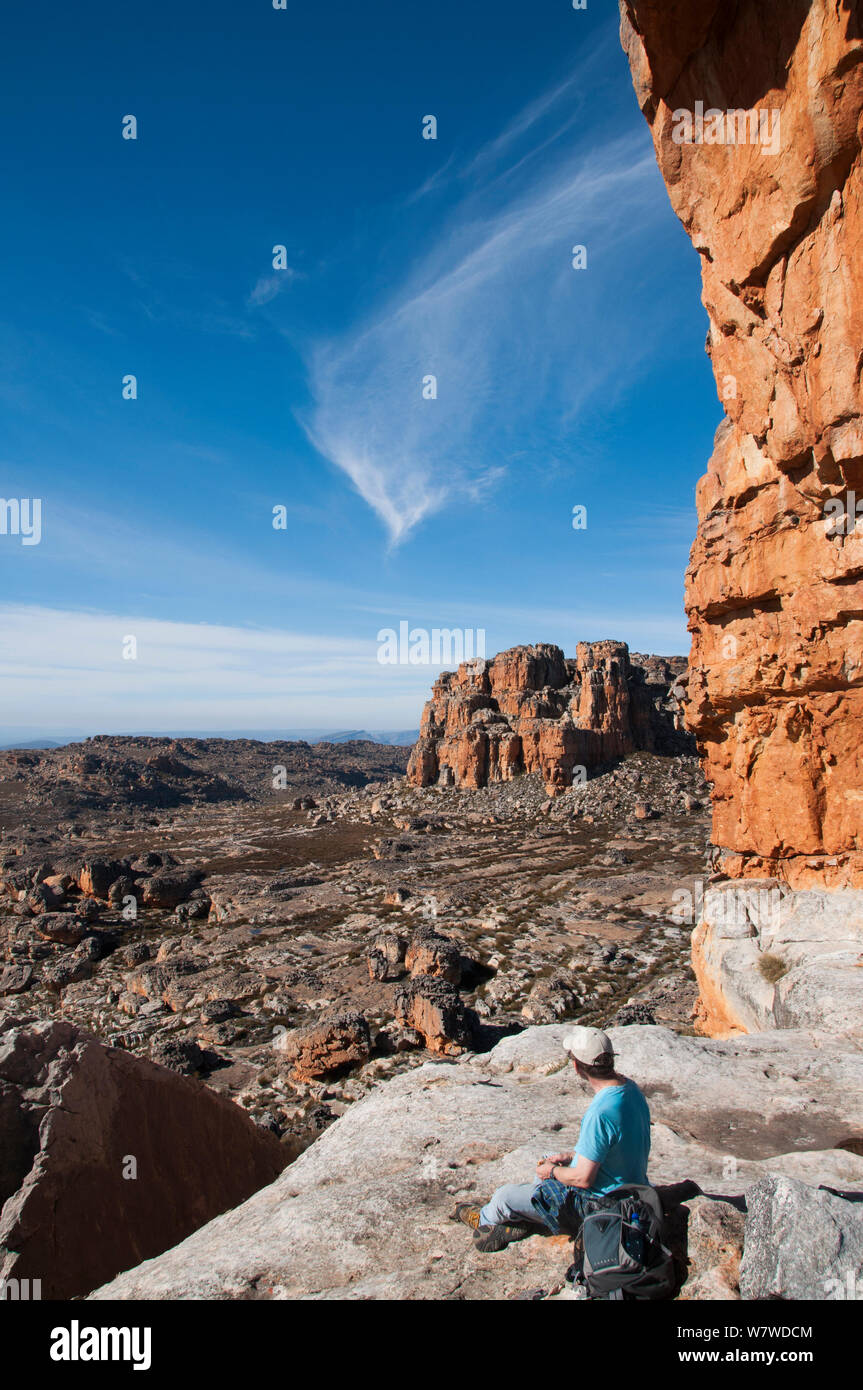 Vista da Wolfberg crepe e arco con uomo seduto sulla roccia, Cederberg Conservancy, Sud Africa, Agosto 2011. Foto Stock