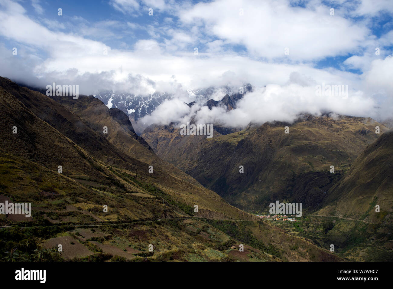 Il villaggio Totoral con montagna Illimani parzialmente oscurata da nuvole in lontananza, alto Ande, Bolivia, ottobre 2013. Foto Stock