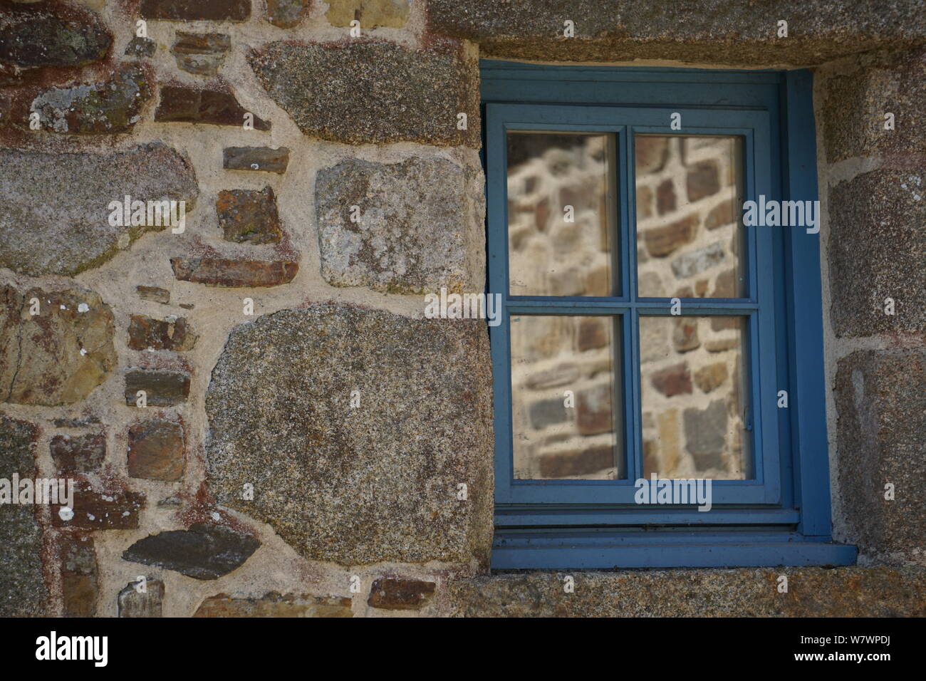 In prossimità di un antico muro di pietra con diverse rocce e riflessione a specchio in una finestra Foto Stock