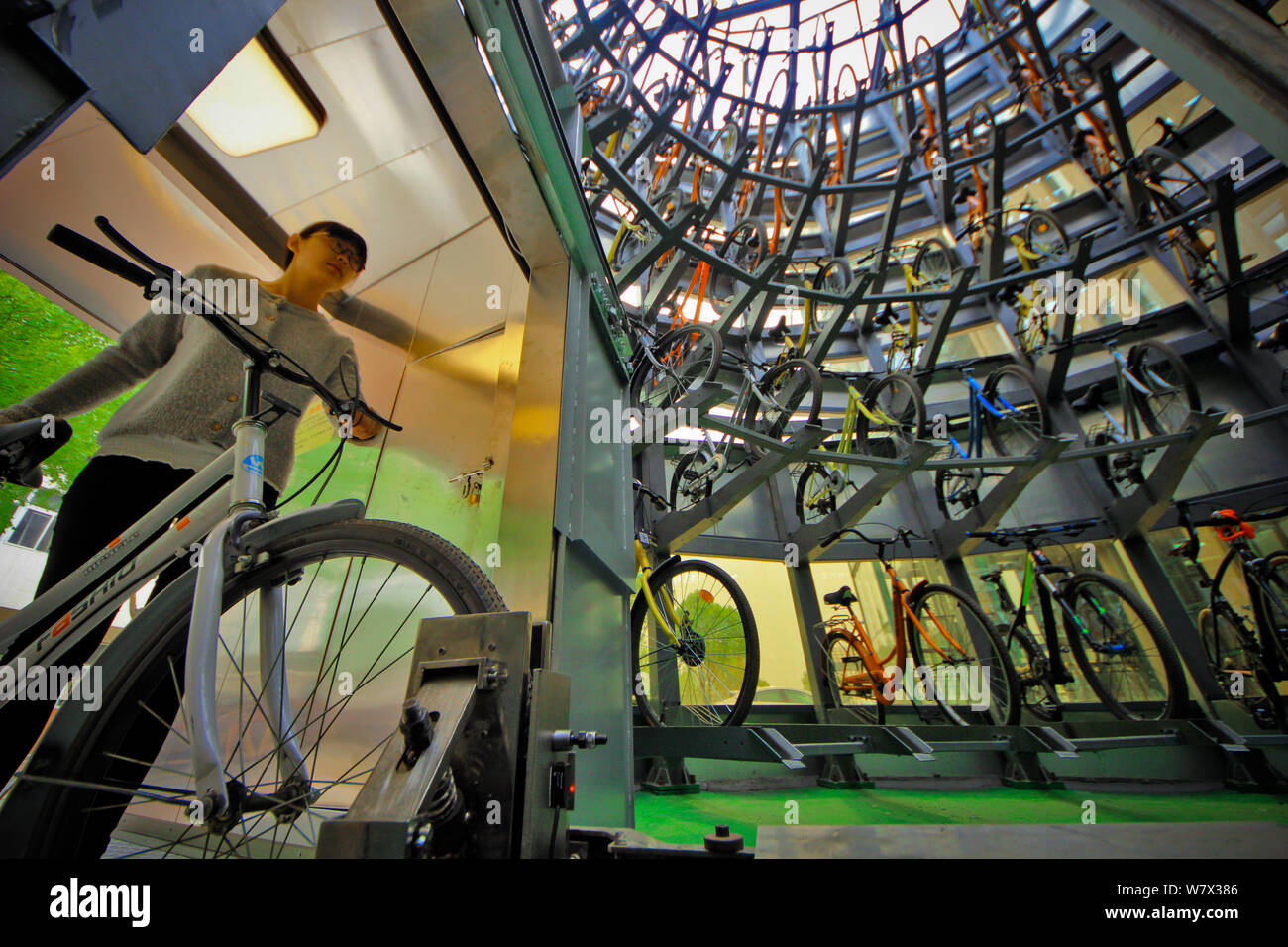 Uno studente cinese di bicicletta parchi attraverso la bicicletta automatico sistema di parcheggio con ID o la carta dello studente nella struttura cilindrica di otto metri tal Foto Stock