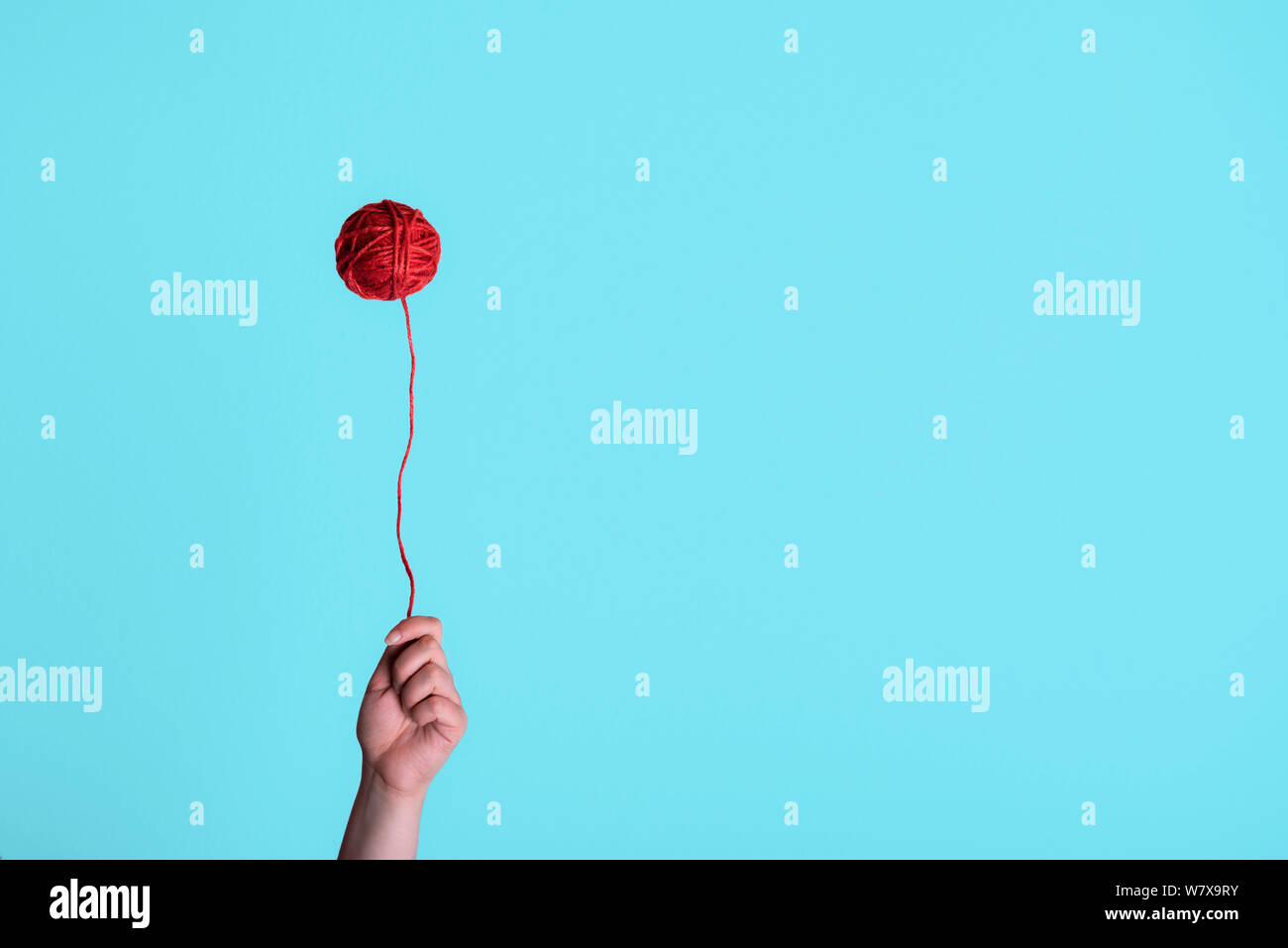 Filo rosso sfera, mobile come un palloncino e una donna mano azienda it. Strano concetto di infanzia. Stile minimal maglia contesto. Foto Stock