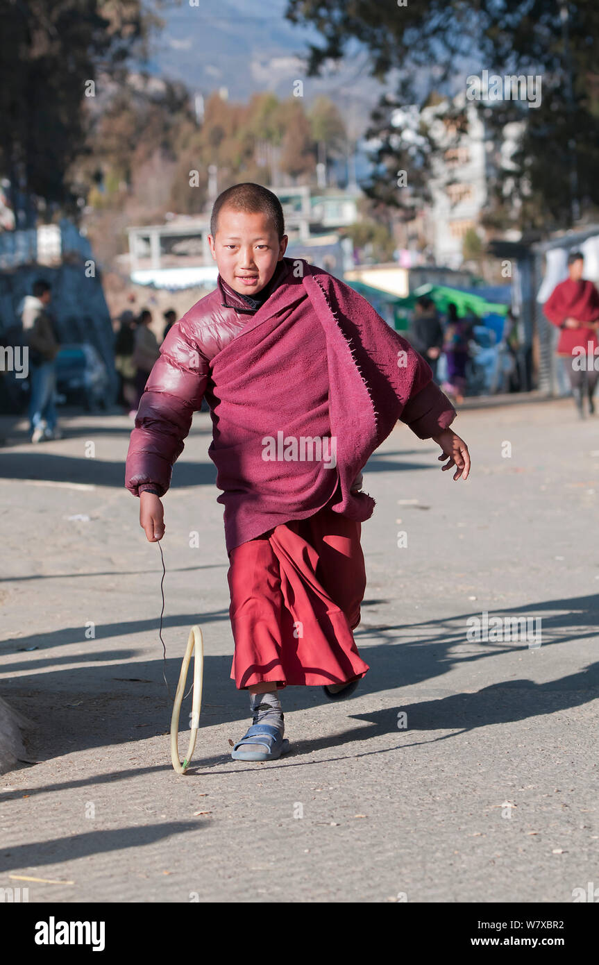 Giovane monaco giocando con fatti in casa hoop giocattolo Torgya durante il festival. Galdan Namge Lhatse Monastero Tawang, Arunachal Pradesh, India. Gennaio 2014. Foto Stock