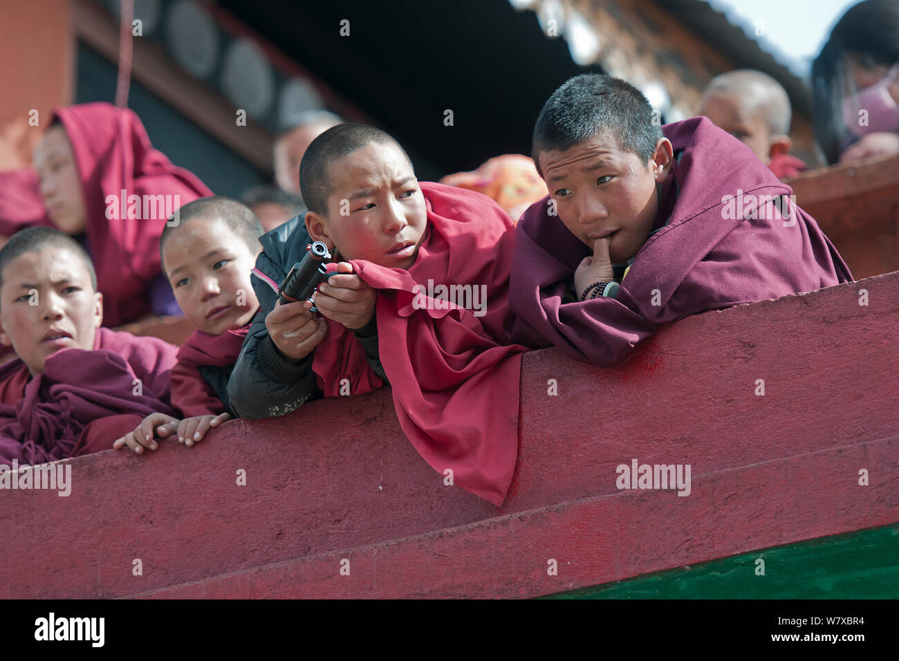 Giovani monaci agli spettatori al festival Torgya con plastica pistola giocattolo. Galdan Namge Lhatse monastero,Tawang, Arunachal Pradesh, India. Gennaio 2014. Foto Stock