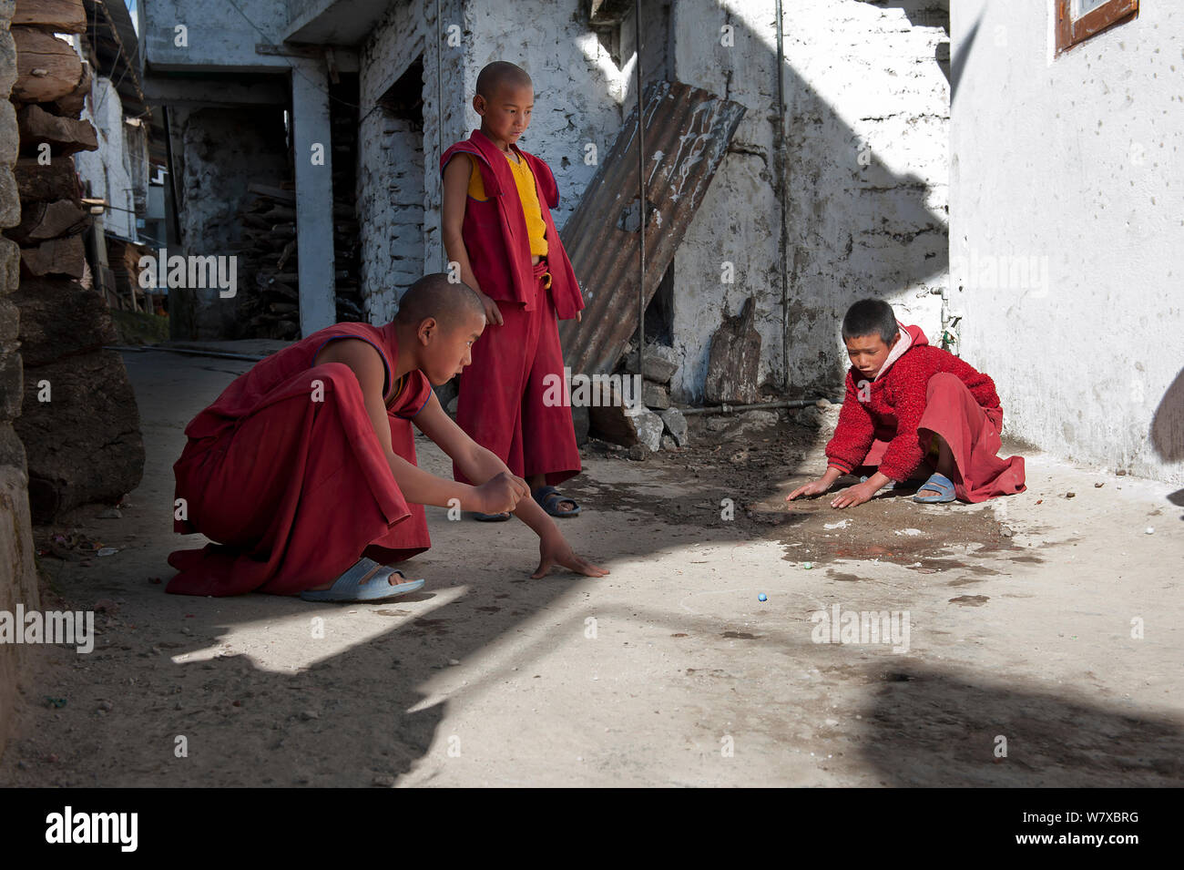Giovani monaci la riproduzione di marmi durante una pausa al festival Torgya. Galdan Namge Lhatse Monastero Tawang, Arunachal Pradesh, India. Gennaio 2014. Foto Stock