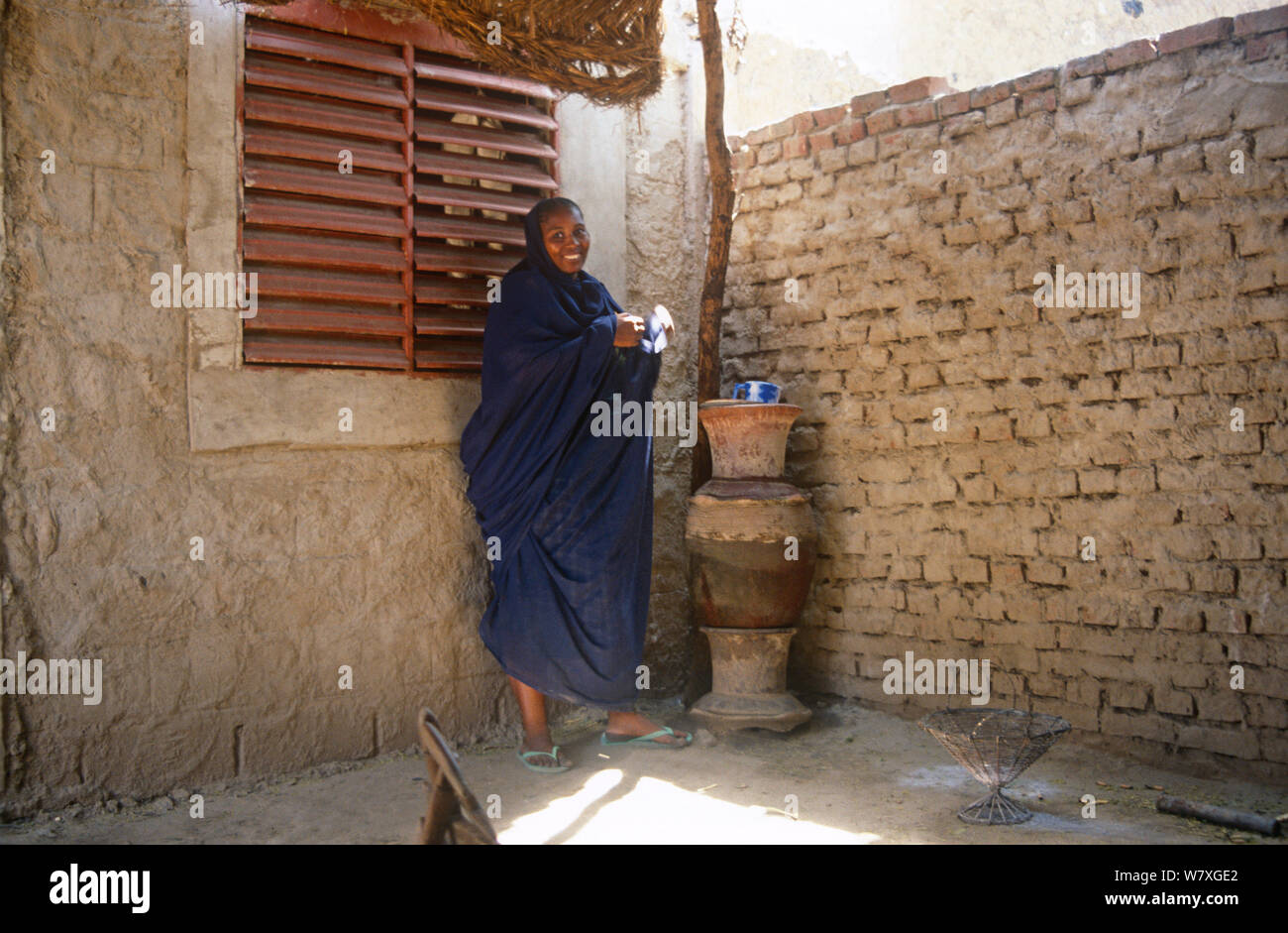 Donna di bere acqua immagazzinata nel vaso di terracotta. N&#39;Djamena, Ciad, 2002-2003. Foto Stock