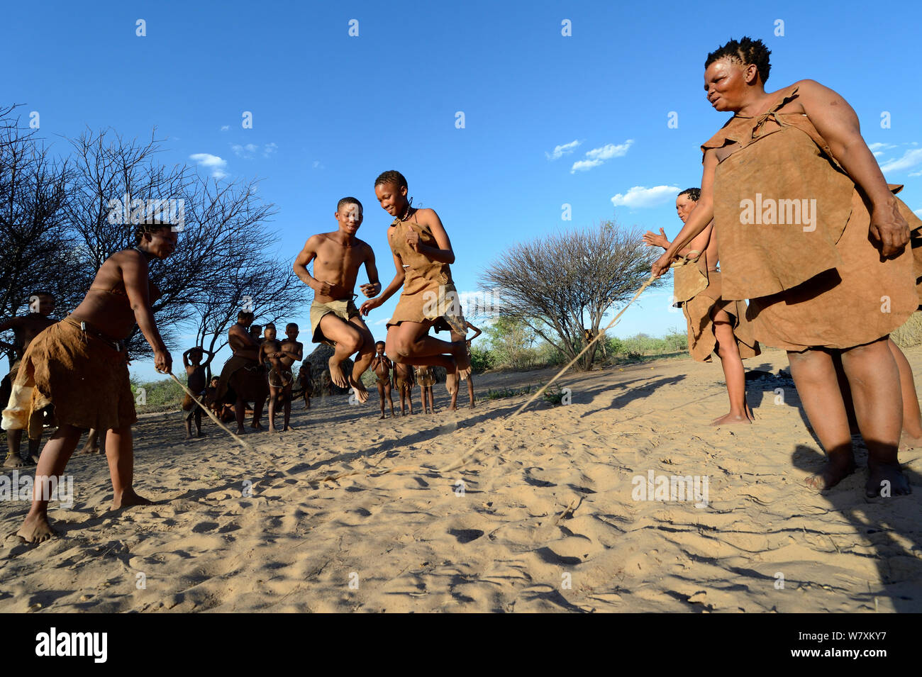 Naro Boscimani San famiglia, donne e bambini che giocano con la corda, il Kalahari, Ghanzi regione, Botswana, Africa. La stagione secca, ottobre 2014. Foto Stock