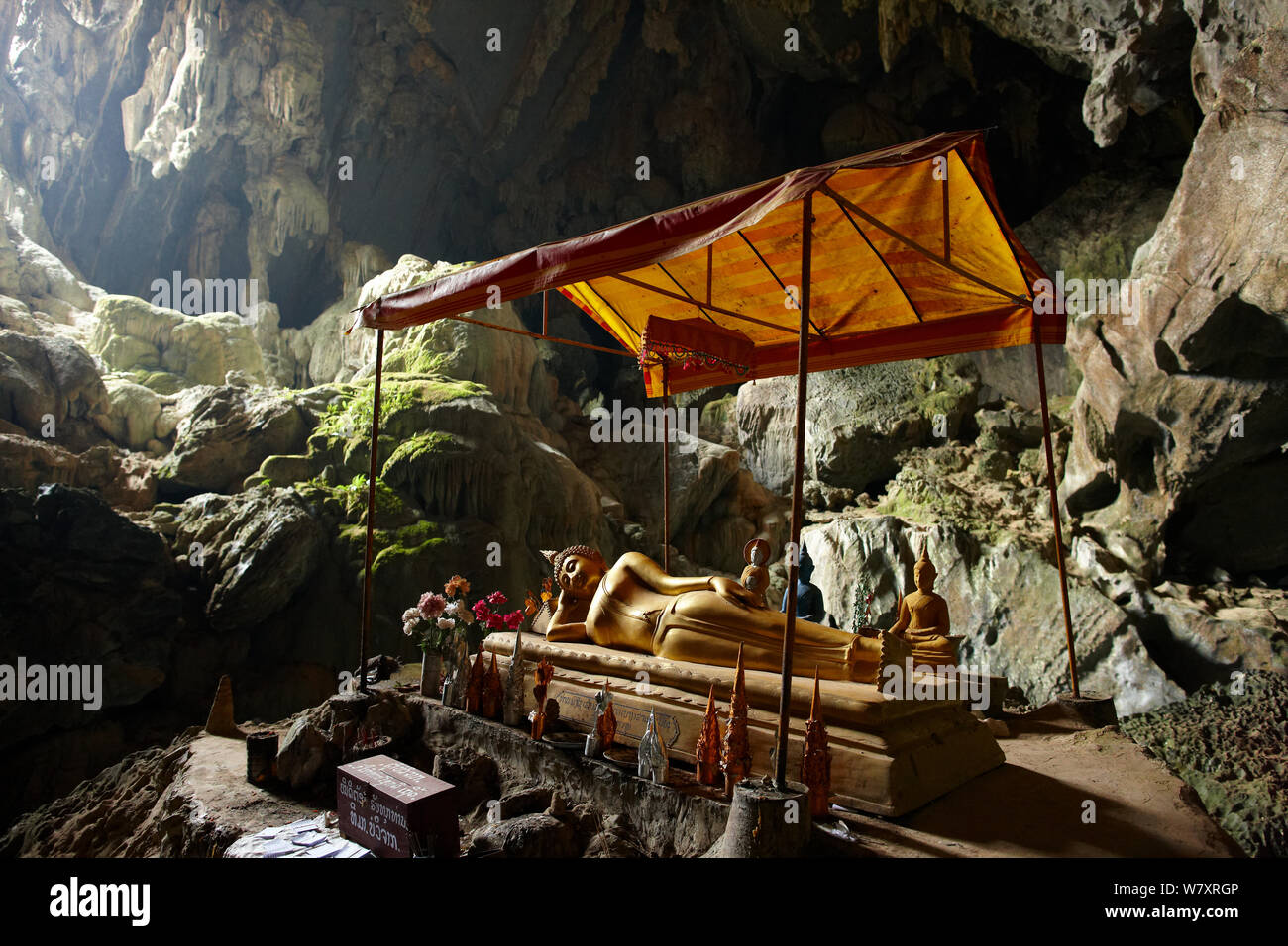 Statua del Buddha reclinato con piccole statue intorno in una grotta e la laguna blu, vicino a Vang Vieng, Laos, marzo 2009. Foto Stock
