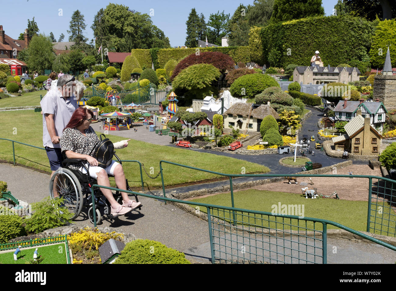 Beaconsfield, Regno Unito - 27 giugno 2019. Una donna disabile su sedia a rotelle visite Bekonscot model village e dalla stazione ferroviaria, una popolare attrazione turistica in strappi Foto Stock