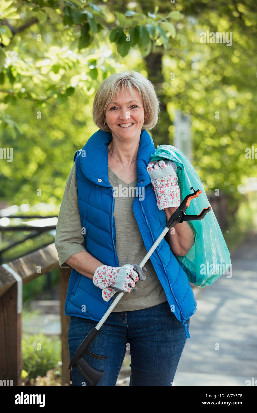 Un ritratto di una donna matura in piedi in un parco, partecipando a una città pulita. Foto Stock