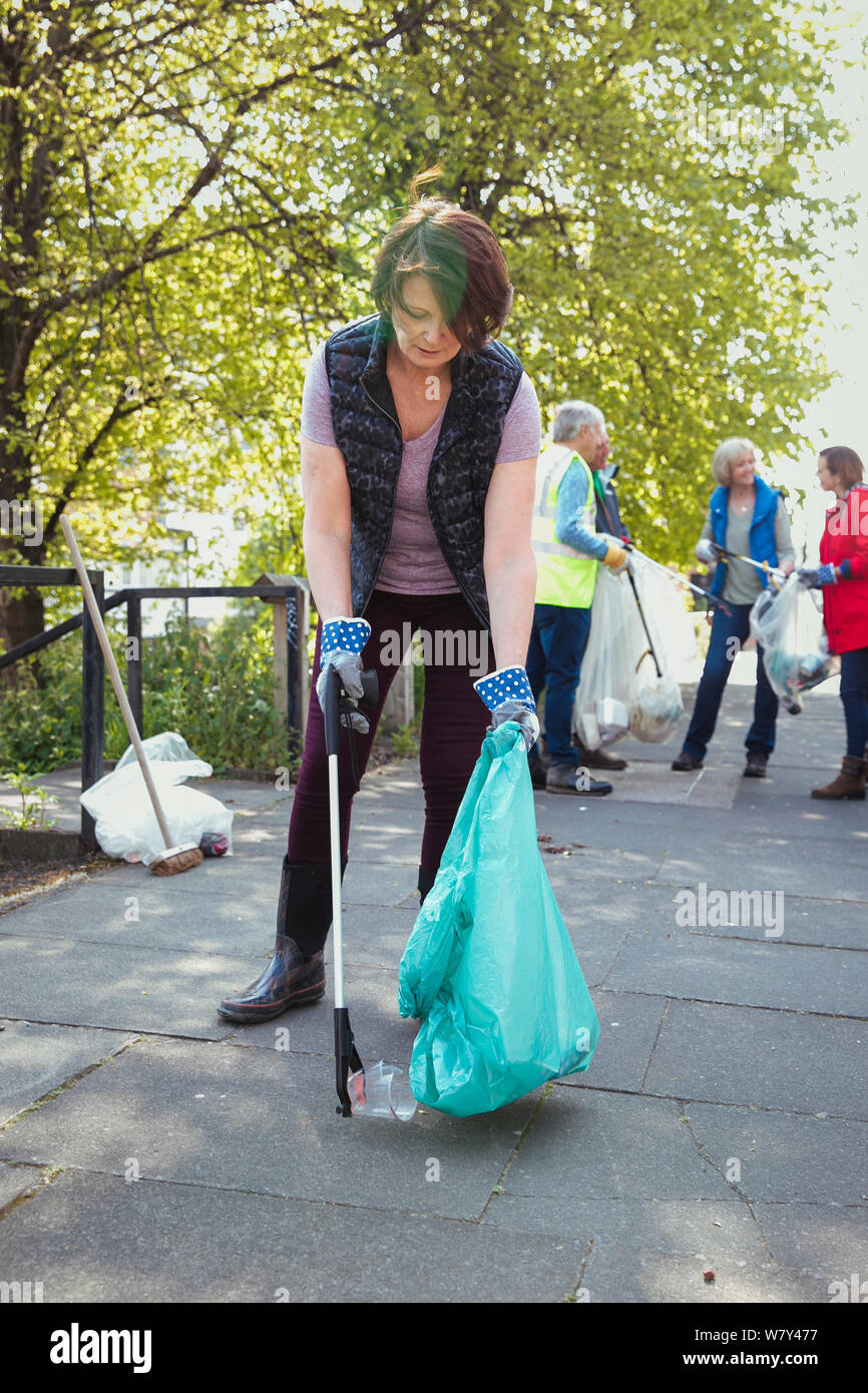 Una donna di prelevare un bicchiere di plastica, partecipando a una città pulita-fino all'esterno. Foto Stock
