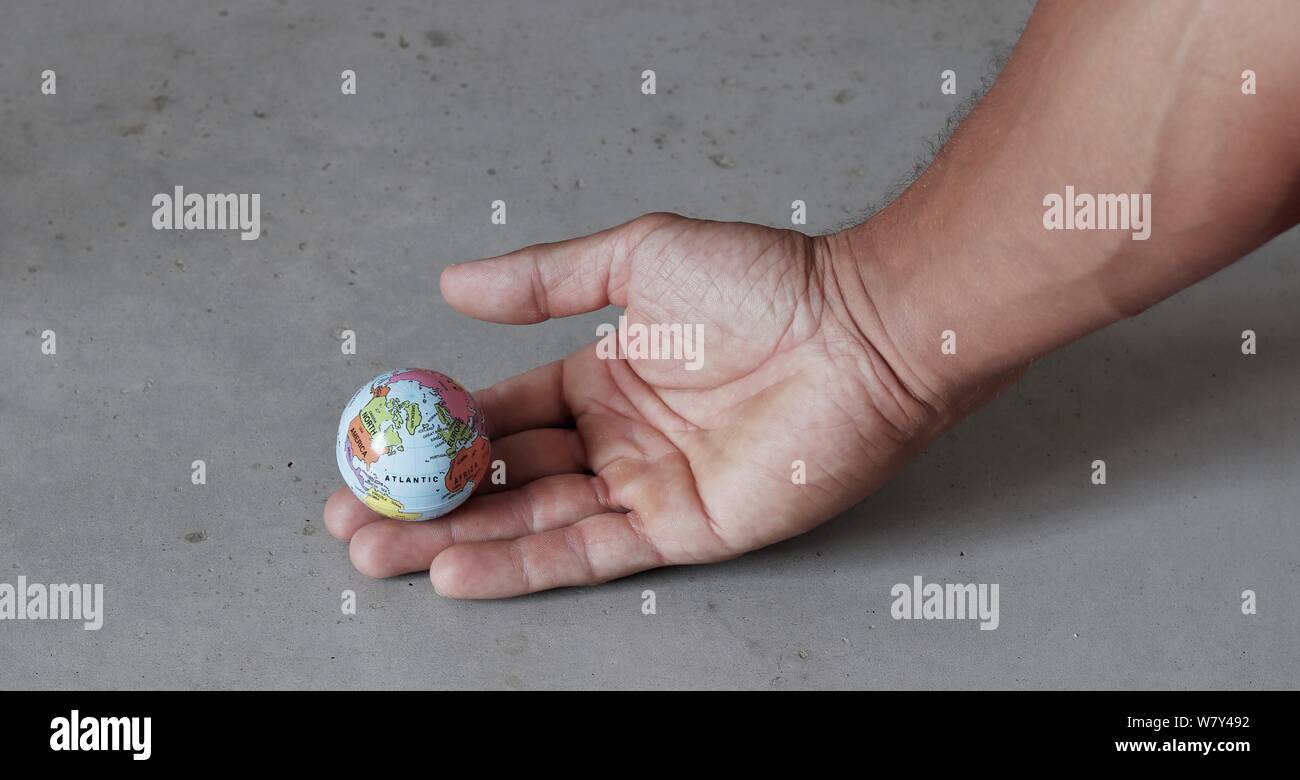 Piccolo mondo a portata di mano con cemento grigio Sfondo visto dal lato. Mondo nelle nostre mani con enironmental conservazione. Foto Stock