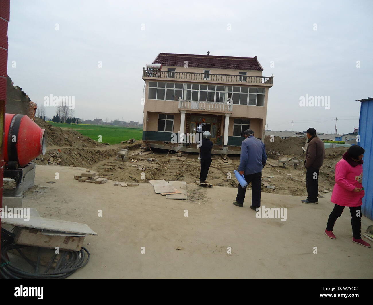 Gli abitanti dei villaggi locali guardare la casa a tre piani spostati dal suo proprietario per fare la strada per la costruzione di una strada provinciale in città Zhuyuan, Taixin Foto Stock