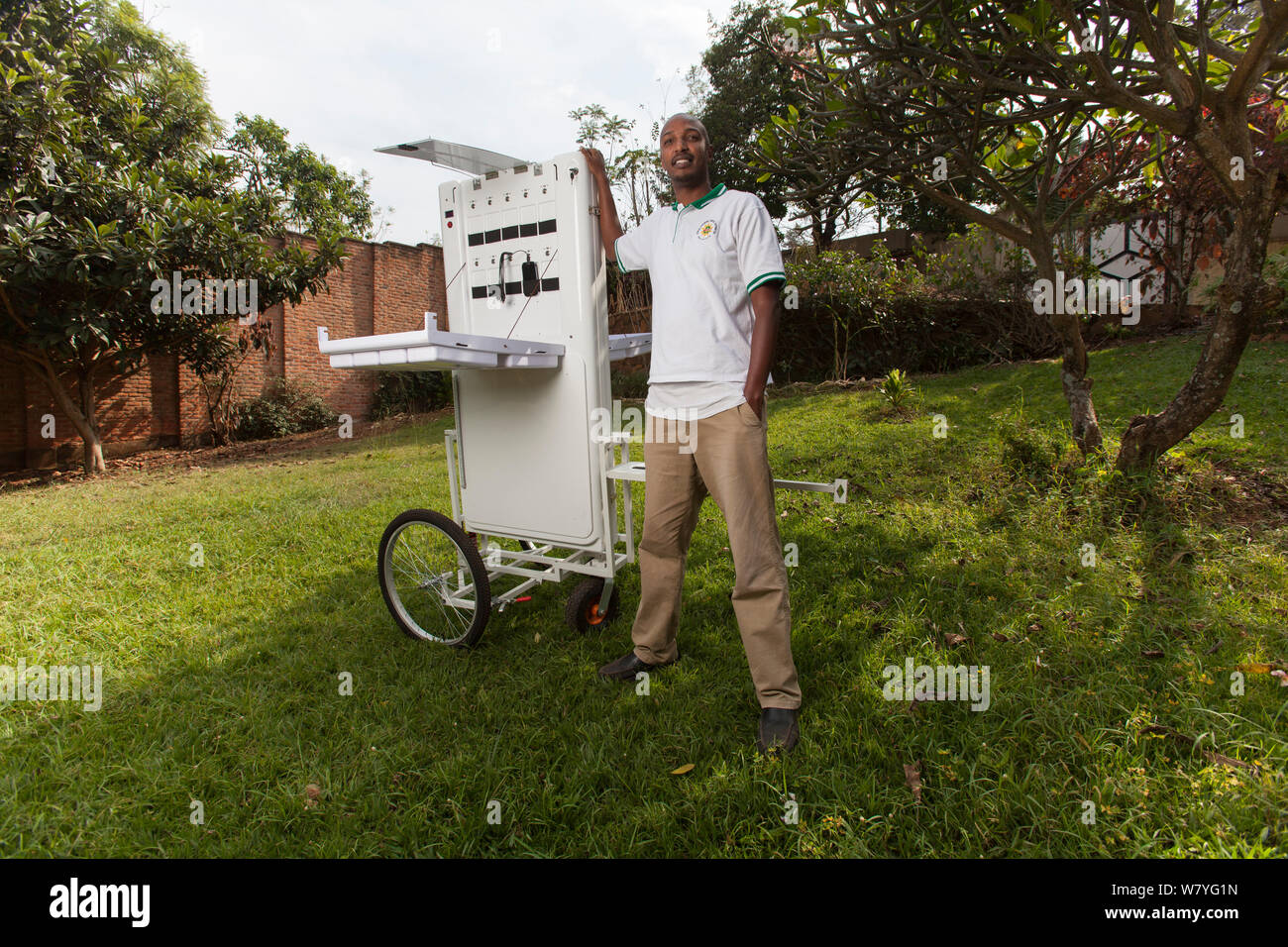 Energia solare imprenditore pone con il suo chiosco solare. (Due 40w pannelli solari ricaricare una batteria agli ioni di litio che può caricare fino a 30 dispositivi elettronici in un momento) Kigali, Ruanda, Giugno 2014. Foto Stock