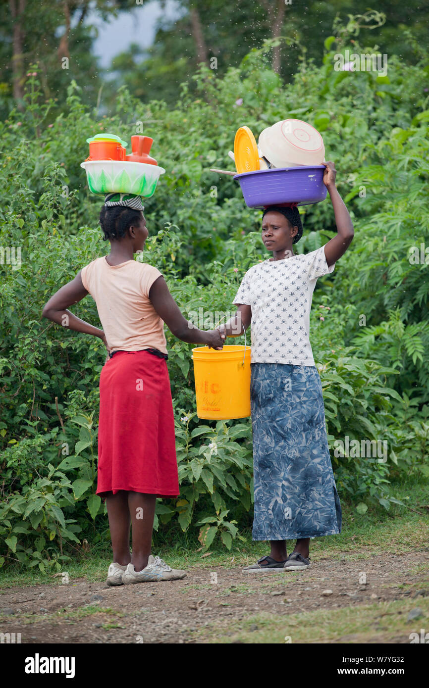 Le donne di parlarsi mentre trasportano cesti in plastica sulle loro teste, Mfangano Island, il lago Victoria, Kenya, febbraio 2013. Foto Stock