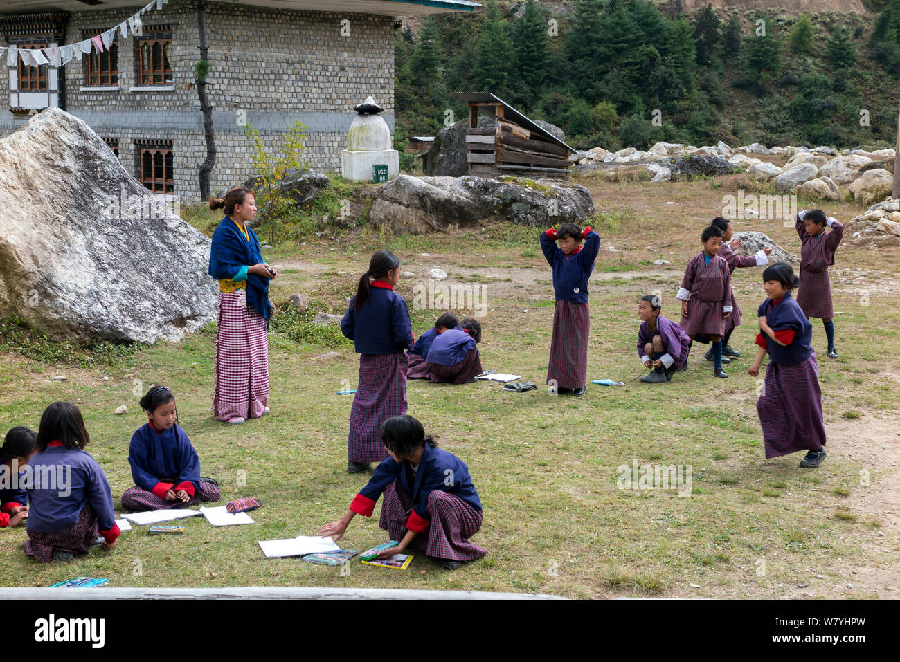 I bambini a scuola di un parco giochi per bambini con insegnante permanente per lato, Paro River Valley. Il Bhutan, ottobre 2014. Foto Stock