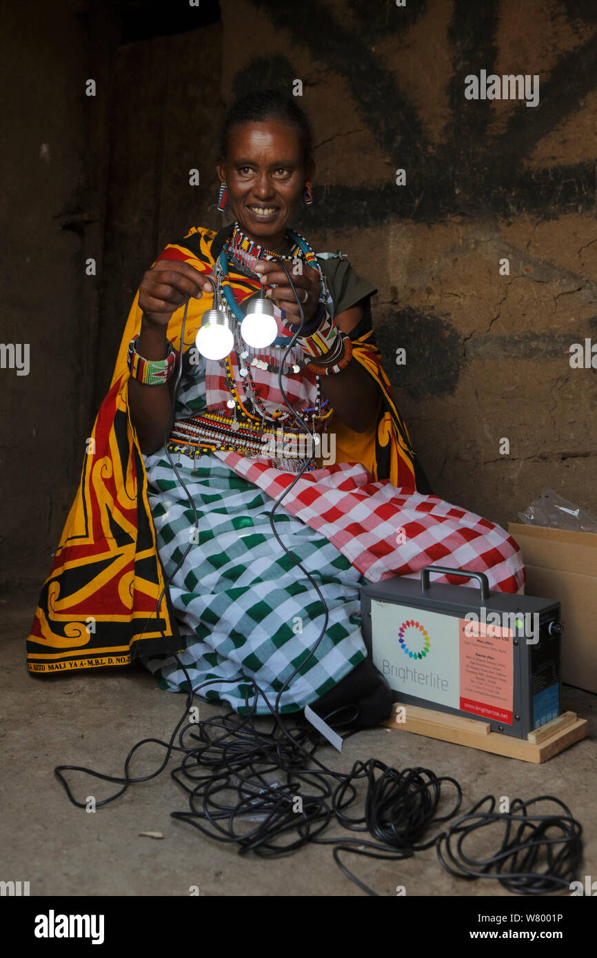 Masai donna con energia solare luci, capanna Masai Mara, Kenya, marzo 2013. Foto Stock
