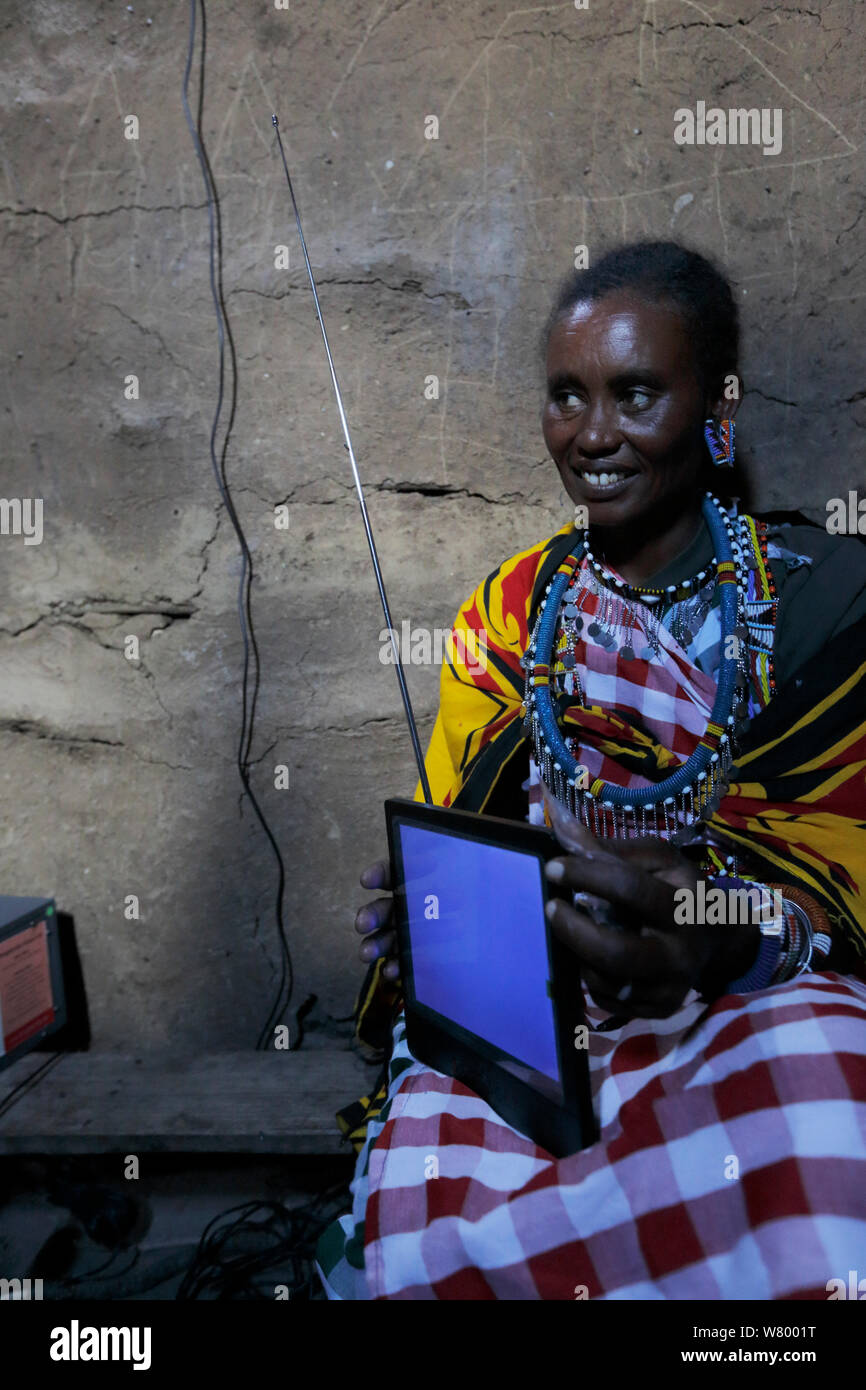 Masai donna con televisore portatile, alimentato da energia solare, il Masai Mara, Kenya. Marzo 2013. Foto Stock