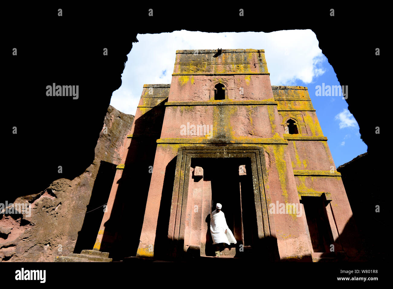 Sacerdote di abbigliamento tradizionale fuori Bet Giyorgis chiesa, una chiesa scavate nella solida roccia di tufo, Lalibela. UNESCO - Sito Patrimonio dell'umanità. Etiopia, dicembre 2014. Foto Stock