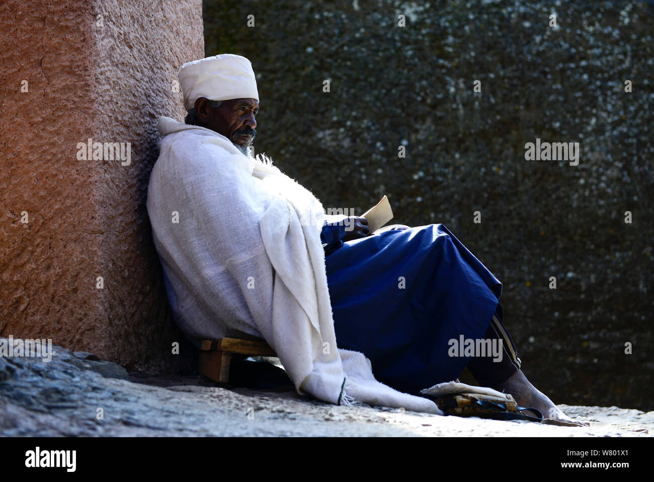 Christian adoratore nelle tradizionali vesti bianche, in appoggio contro la parete, Bet Medhane Alem (parte della Northwestern gruppo di chiese di Lalibela). UNESCO - Sito Patrimonio dell'umanità. Lalibela. Etiopia, dicembre 2014. Foto Stock