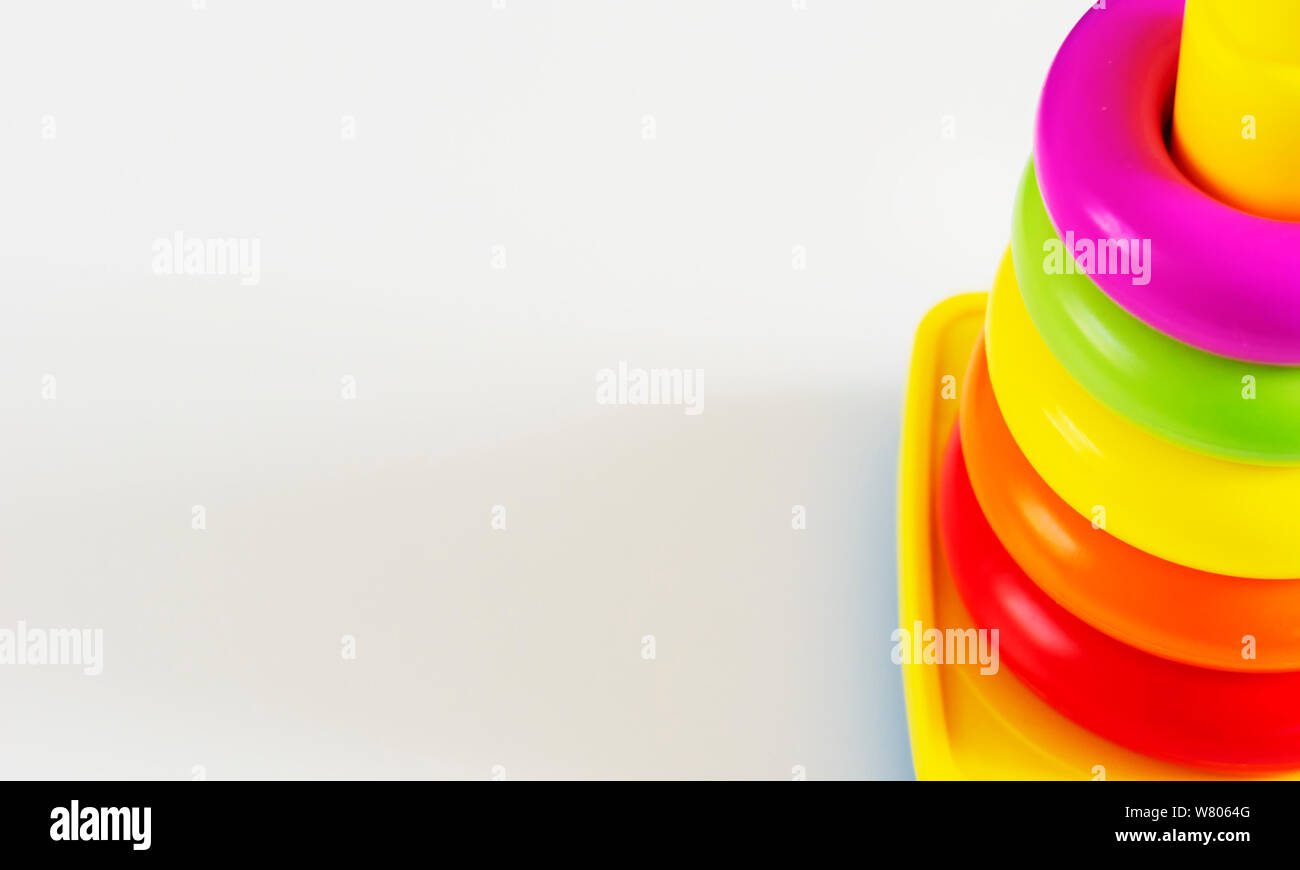 Anelli in materiale plastico di diversi colori sono impilati in un giallo torre di plastica. Gioco educativo per i bambini a sviluppare le loro abilità e creatività Foto Stock