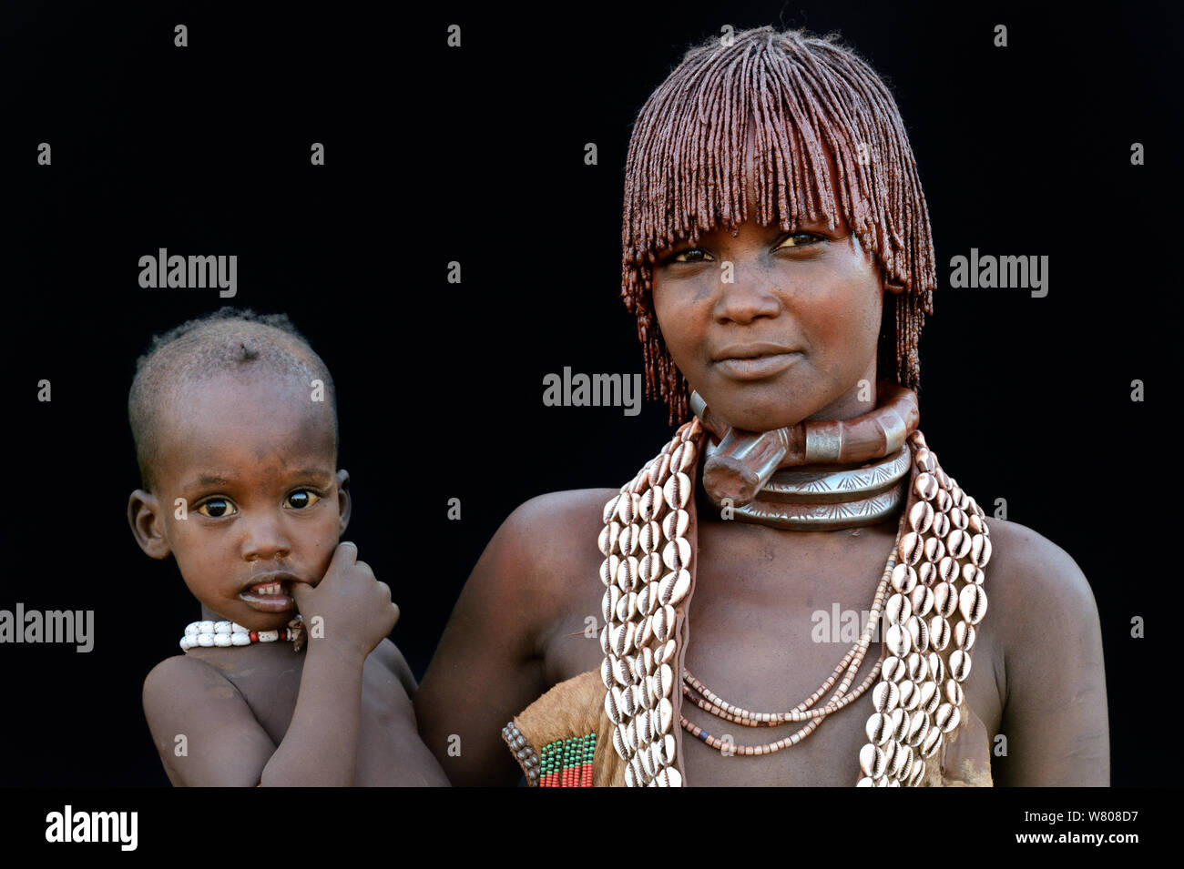 Giovani Hamer tribe Donna con bambino, indossando il tradizionale collane e capelli coperti con una miscela di ocra e grasso animale, valle dell'Omo, Etiopia, marzo 2015. Foto Stock