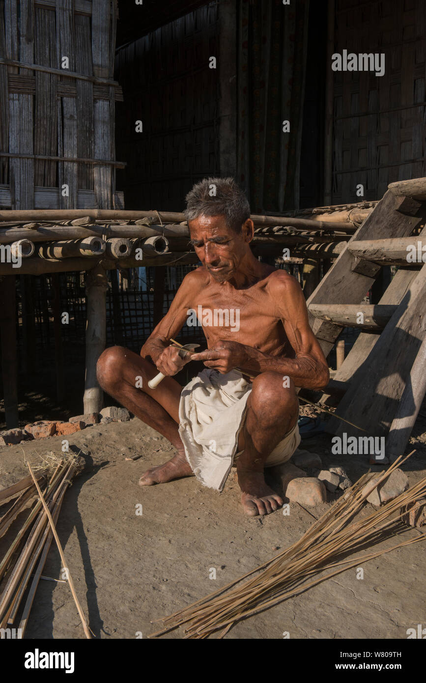 Combinavano Tribe Uomo intrecciando cestini di canna, Majuli Island, fiume Brahmaputra, Assam, nel nord est dell'India. Ottobre 2014. Foto Stock