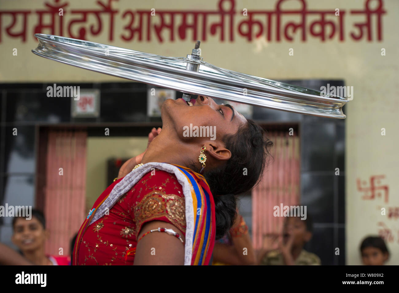 Hijra performer, equilibratura ruota di bicicletta sui denti. Hijra sono transgender gente legalmente riconosciuto come un terzo sesso in India. Uttar Pradesh, India, ottobre 2014. Foto Stock