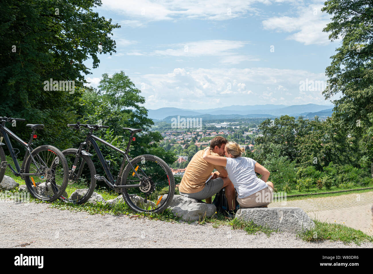 Lubiana, Slovenia. Il 3 agosto 2019. Un giovane seduto davanti al panorama visto dalla collina del castello della città Foto Stock