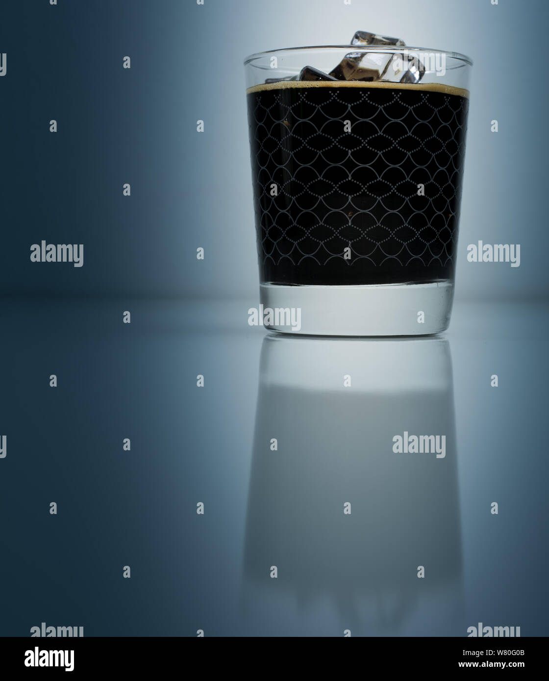 Caffè ghiacciato in elegante calice isolato su sfondo blu scuro Foto Stock