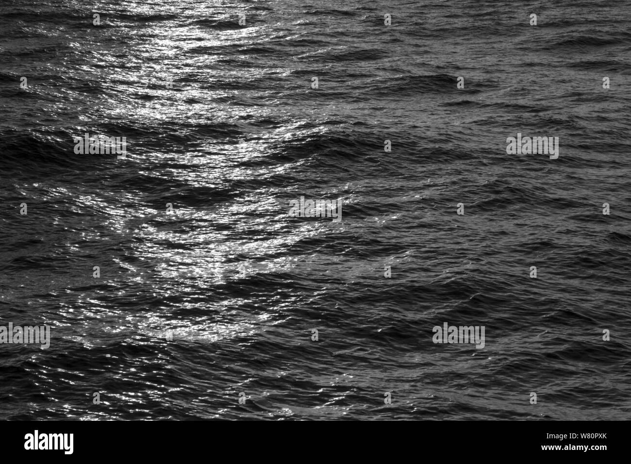 Tramonti riflessi delle luci sulle onde in bianco e nero Foto Stock