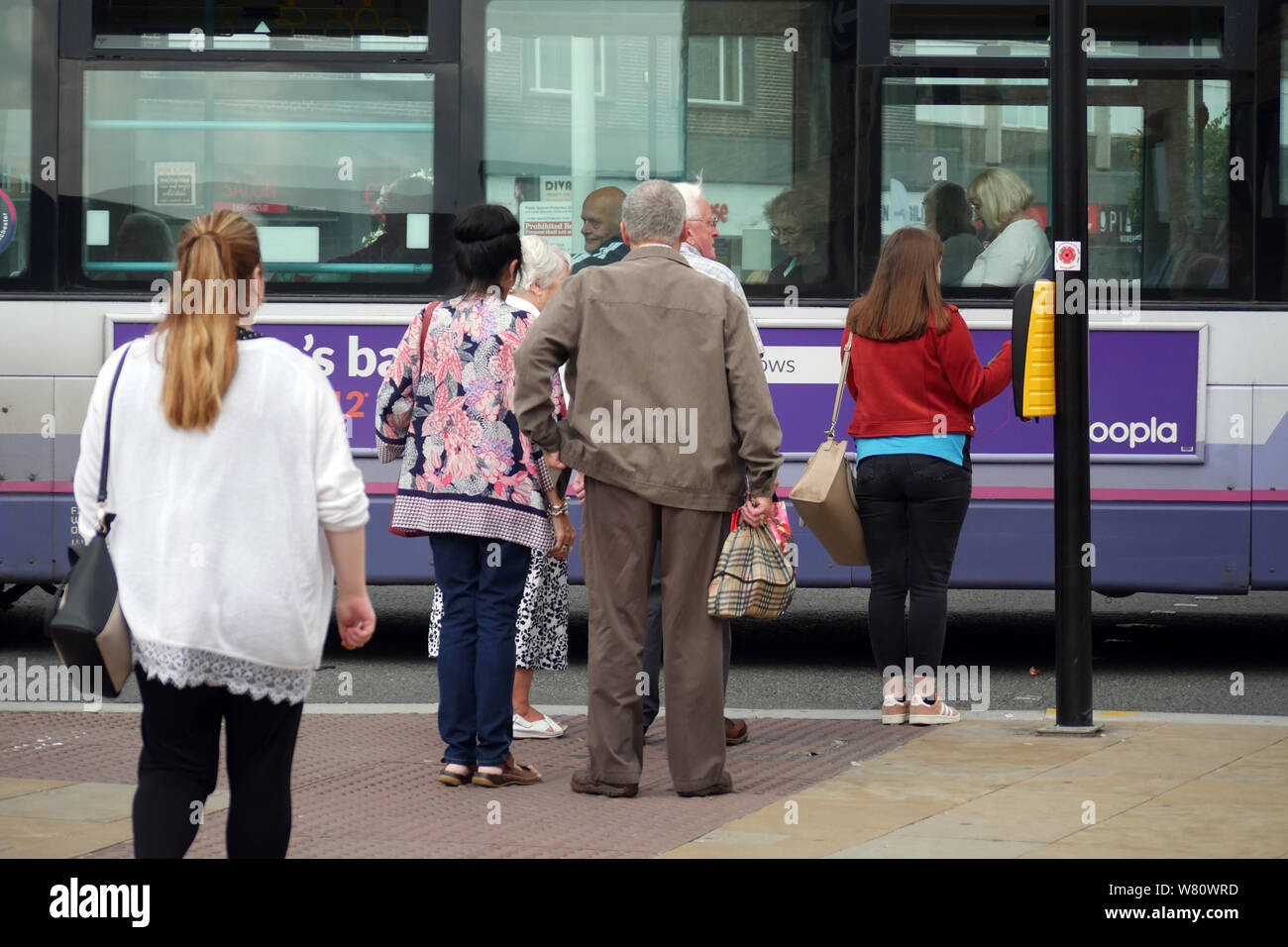 Pedoni premere il pulsante e attendere il segnale di traffico per cambiare in modo da poter attraversare una strada trafficata in modo sicuro nel centro di Bolton, England Regno Unito fotografia DON TONGE Foto Stock