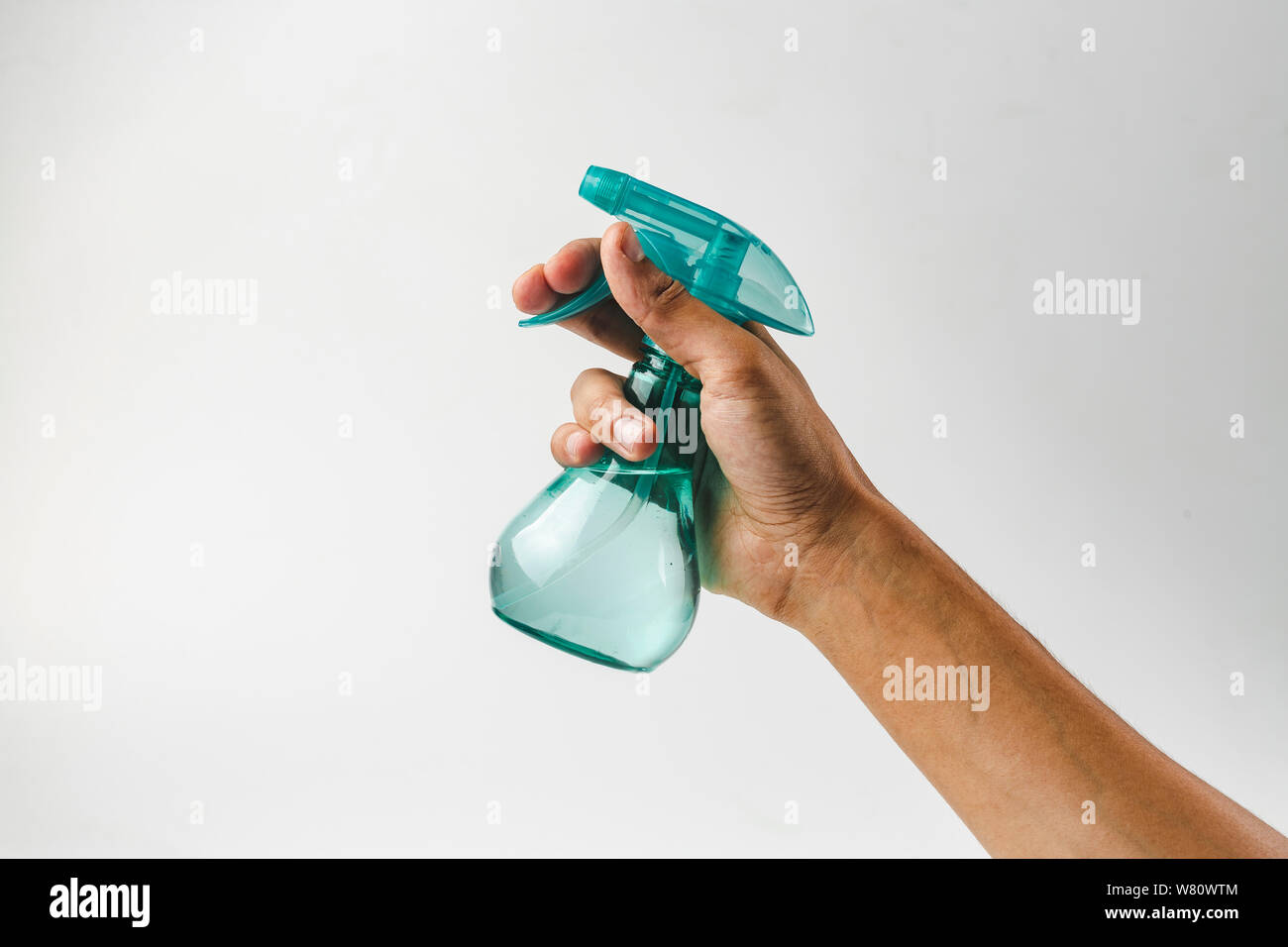 A mano in plastica di contenimento la bottiglia spray - fissare plastica flacone spray isolato su bianco. Uomo con spruzzatore di acqua in mano. Foto Stock