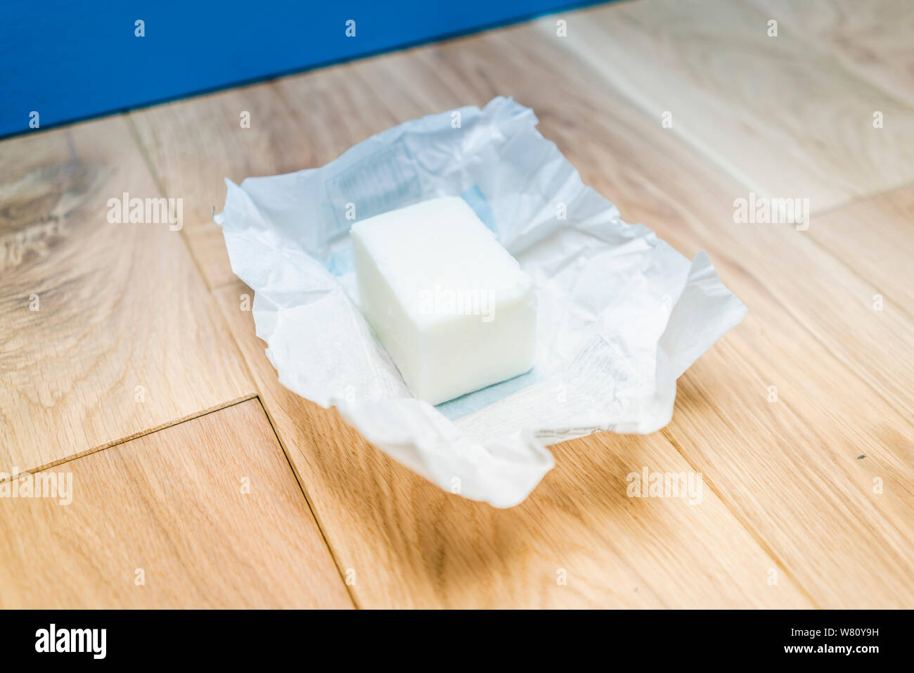 Un grumo di lardo in carta non confezionate su assi di legno simbolica della dieta malsana, grasso di accumulo, cattive abitudini alimentari - e o il corso di un tipo di cibo. Foto Stock