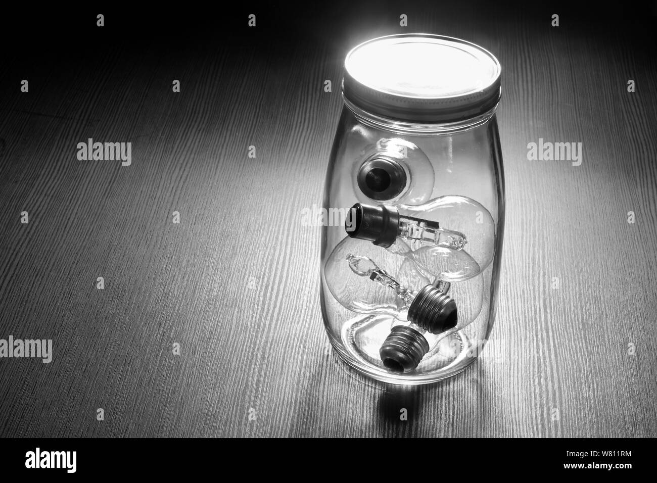 Vaso di vetro con lampadine su sfondo di legno Foto Stock