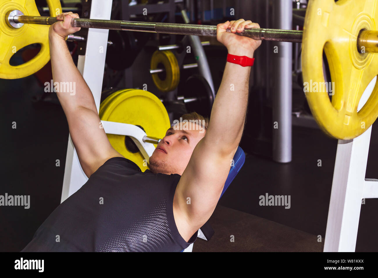 Giovane uomo compie un esercizio barbell pressa da banco dal petto in palestra Foto Stock