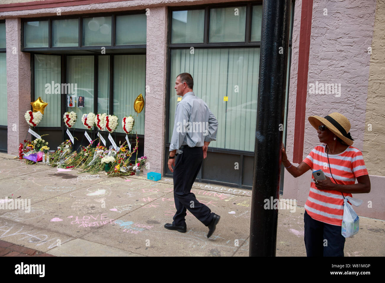 Un uomo cammina passato un memoriale di fronte ad un edificio sulla quinta strada in corrispondenza del sito di domenica mattina la ripresa di massa che ha lasciato 9 morti e 27 feriti, mercoledì 7 agosto 2019 a Dayton, Ohio. Trump ha visitato un ospedale vicino ma non ha visitato il sito della ripresa prima di volare a El Paso, Texas, che fu anche il luogo di una massa di ripresa. Foto Stock