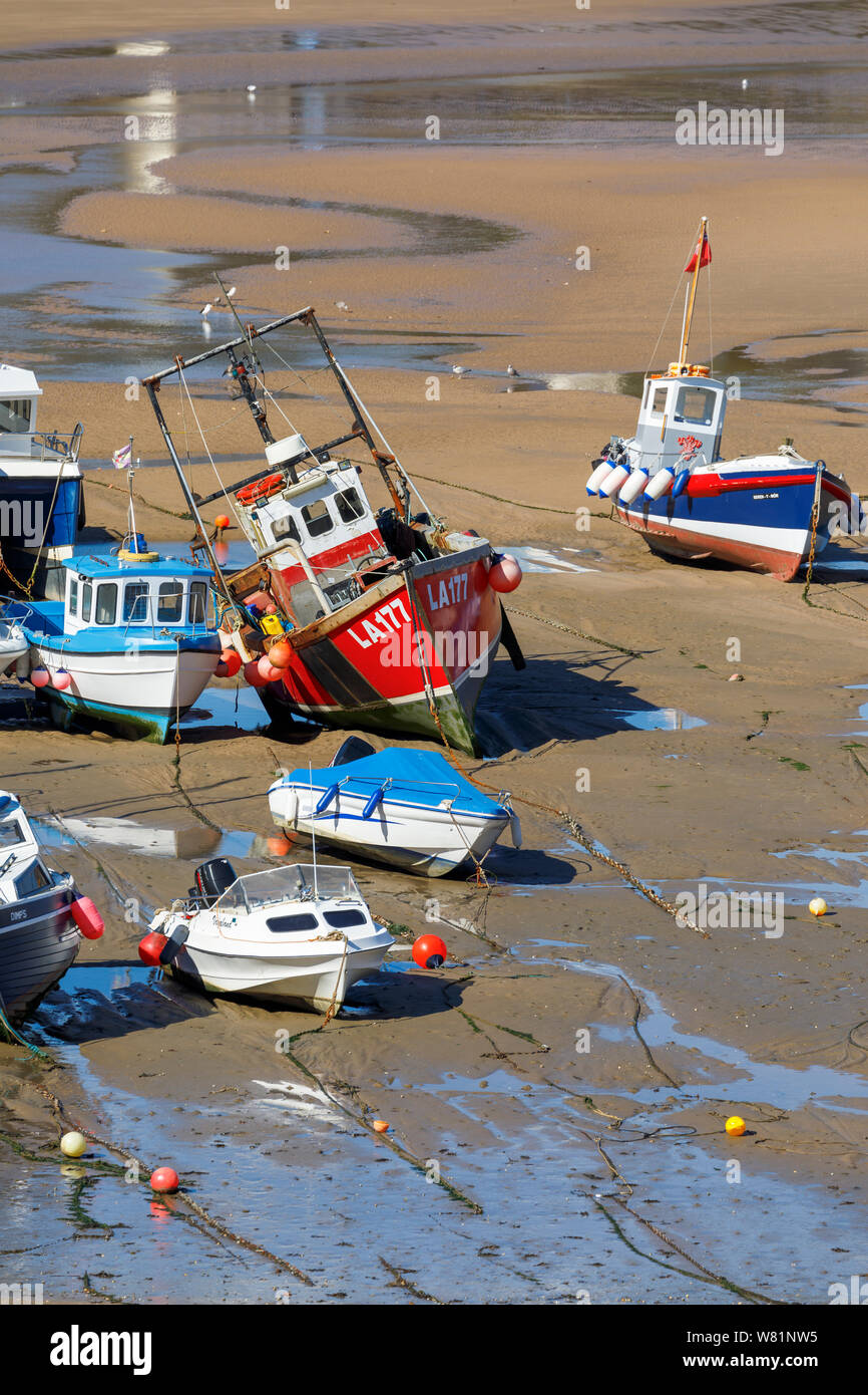 Barche da pesca spiaggiata a bassa marea nel porto di Tenby, una cinta muraria cittadina balneare in Pembrokeshire, Galles del Sud sulla costa ovest della baia di Carmarthen Foto Stock