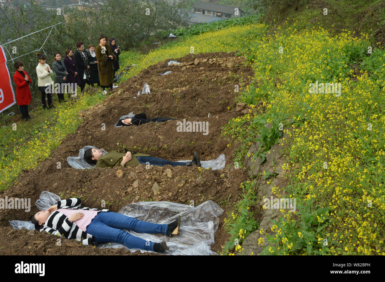 Le donne cinesi giacciono in terra 'tombe' in atto di "cimitero meditazione' durante un insolito rituale per aiutare divorcees far fronte con il loro matrimonio i guasti Foto Stock