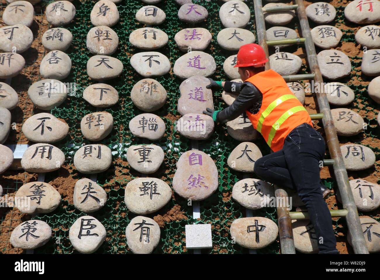 Un lavoratore visualizza rocce scolpite con il testo del classico cinese Tao Te Ching', anche semplicemente indicata come Laozi, sulla montagna Wangwu in Jiyuan Foto Stock