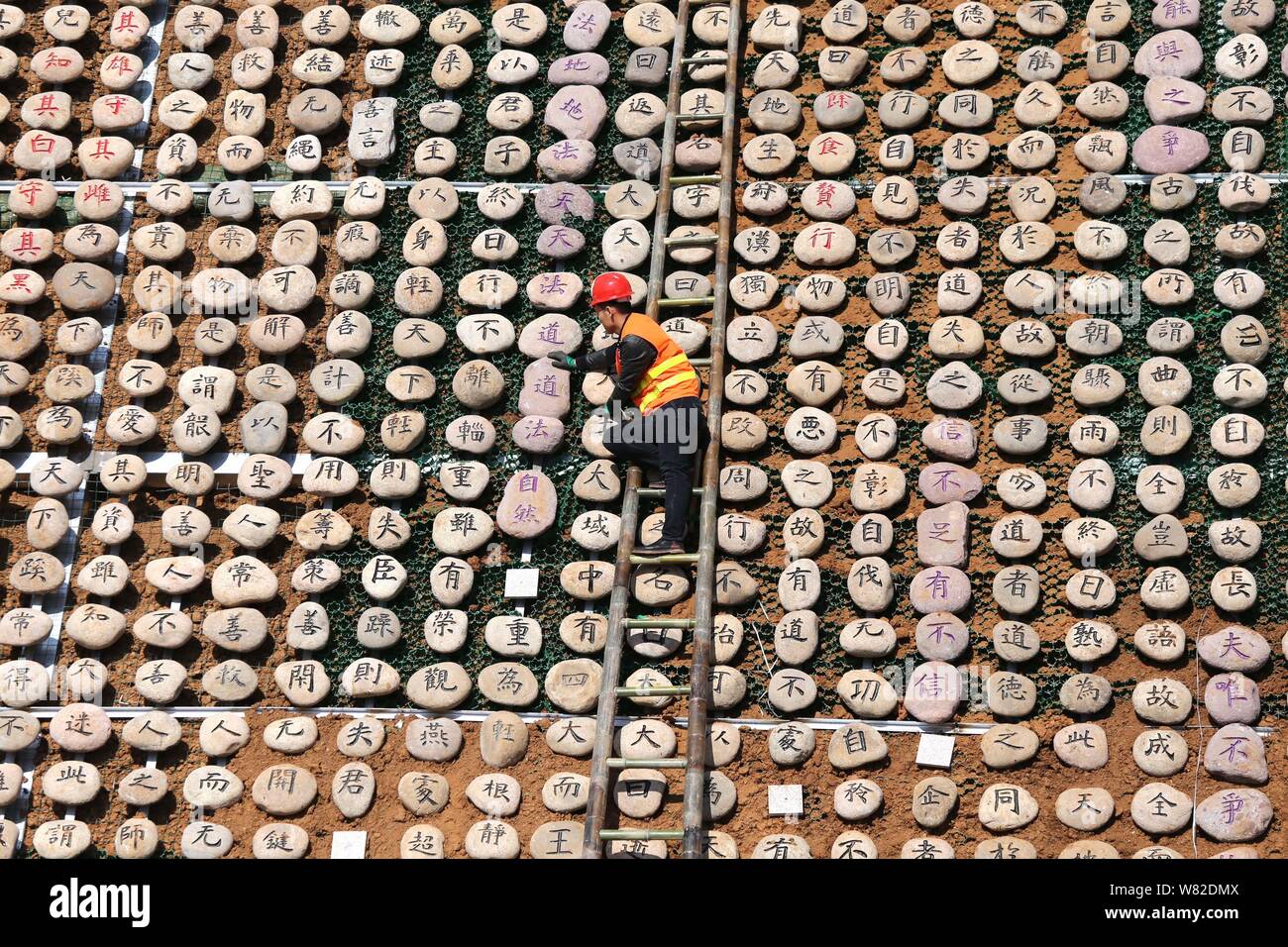 Un lavoratore visualizza rocce scolpite con il testo del classico cinese Tao Te Ching', anche semplicemente indicata come Laozi, sulla montagna Wangwu in Jiyuan Foto Stock