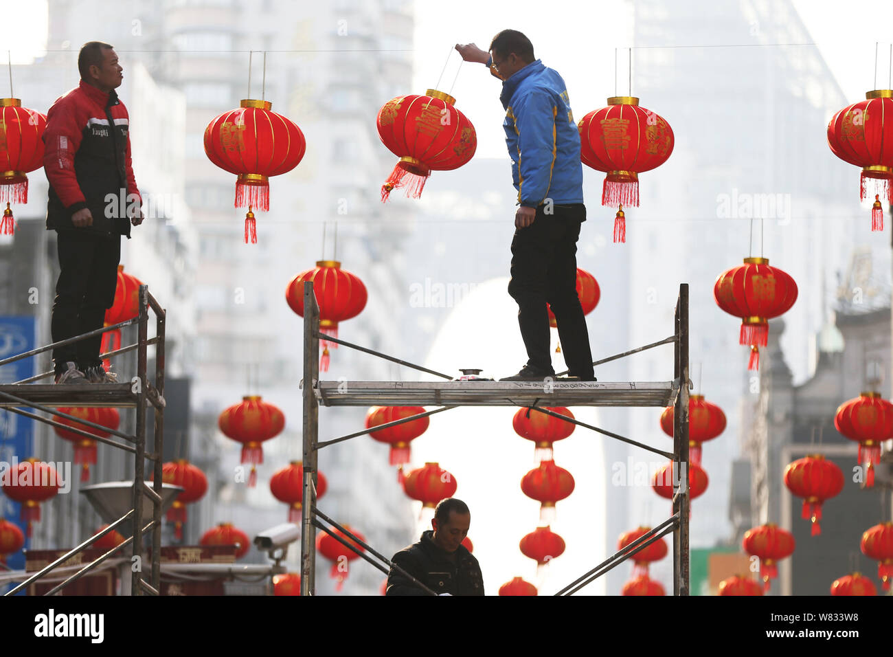 Lavoratori cinesi riagganciare lanterne rosse su una strada pedonale per celebrare la prossima festa della primavera o il nuovo anno cinese (Anno del Gallo) Foto Stock