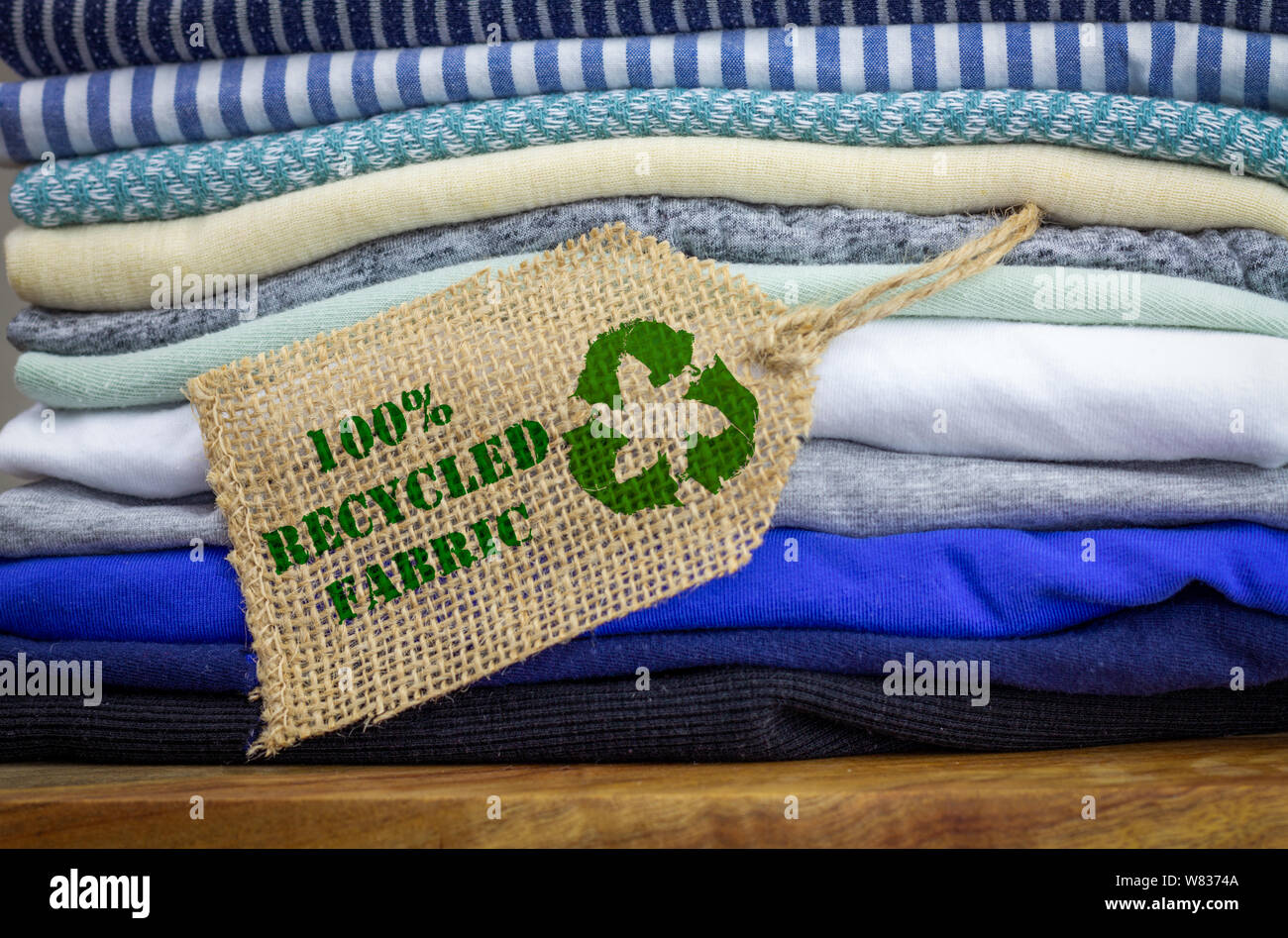 Riciclare i vestiti icona sulla etichetta di tessuto con 100% riciclato testo, concetto illustrazione riutilizzare e riciclare abiti e prodotti tessili per ridurre i rifiuti Foto Stock