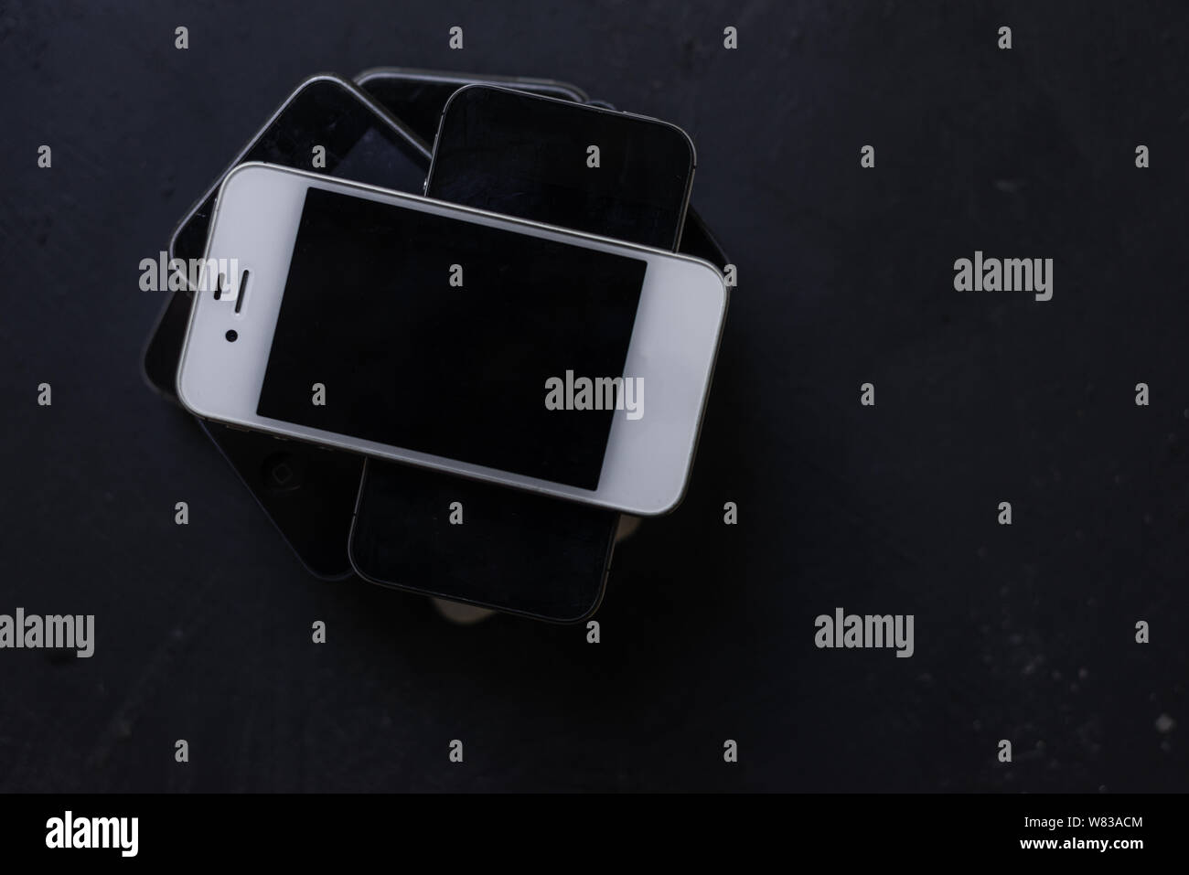 Collezione di vecchi telefoni su sfondo nero, obsoleto cellulare rotto Foto Stock