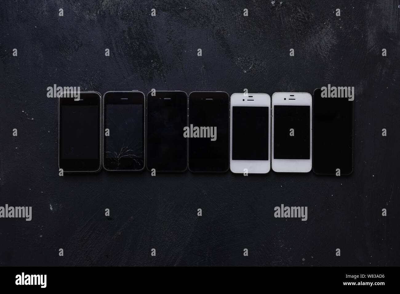 Collezione di vecchi telefoni su sfondo nero, obsoleto cellulare rotto Foto Stock