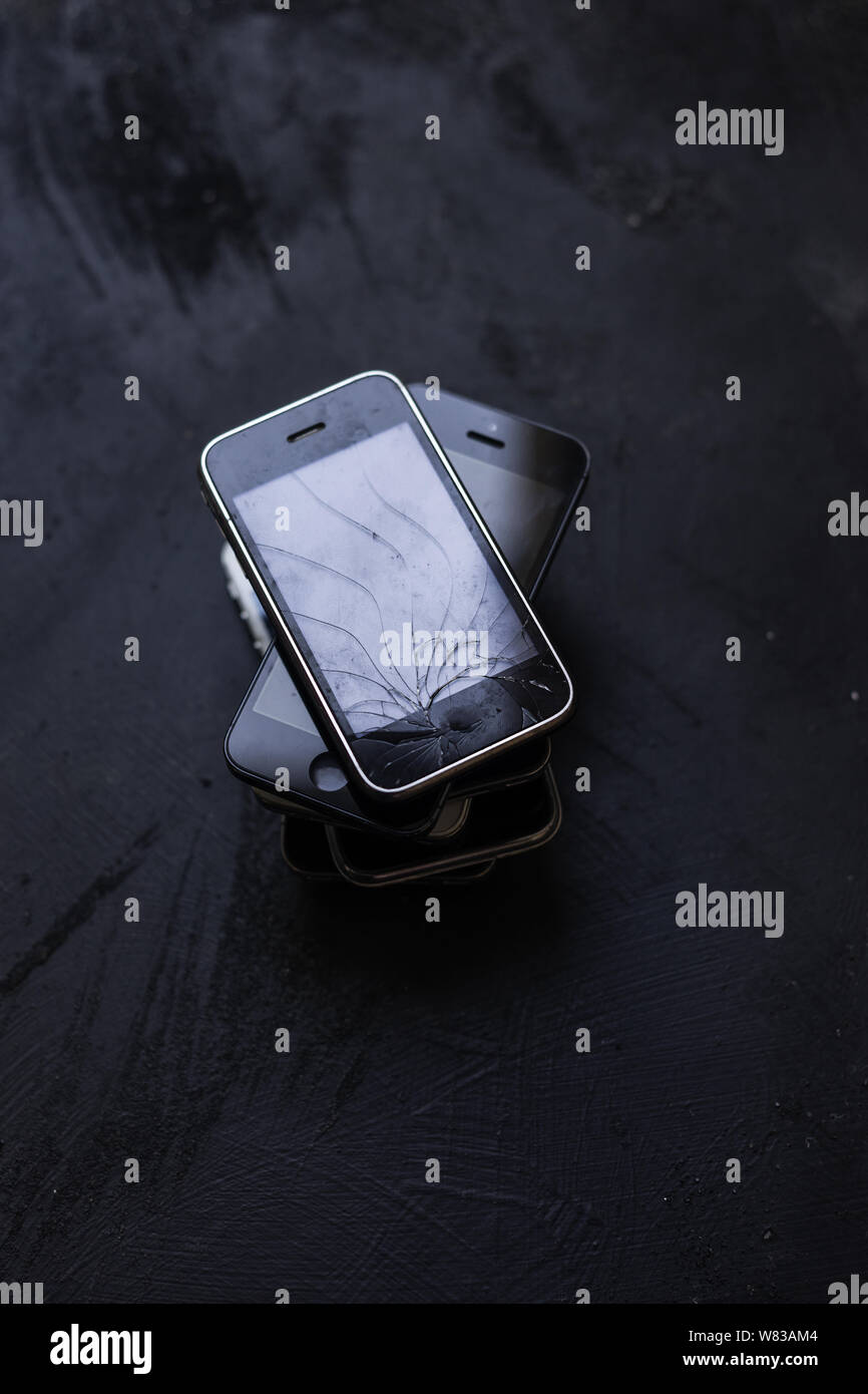 Collezione di vecchi telefoni su sfondo nero, obsoleto cellulare rotto Foto Stock