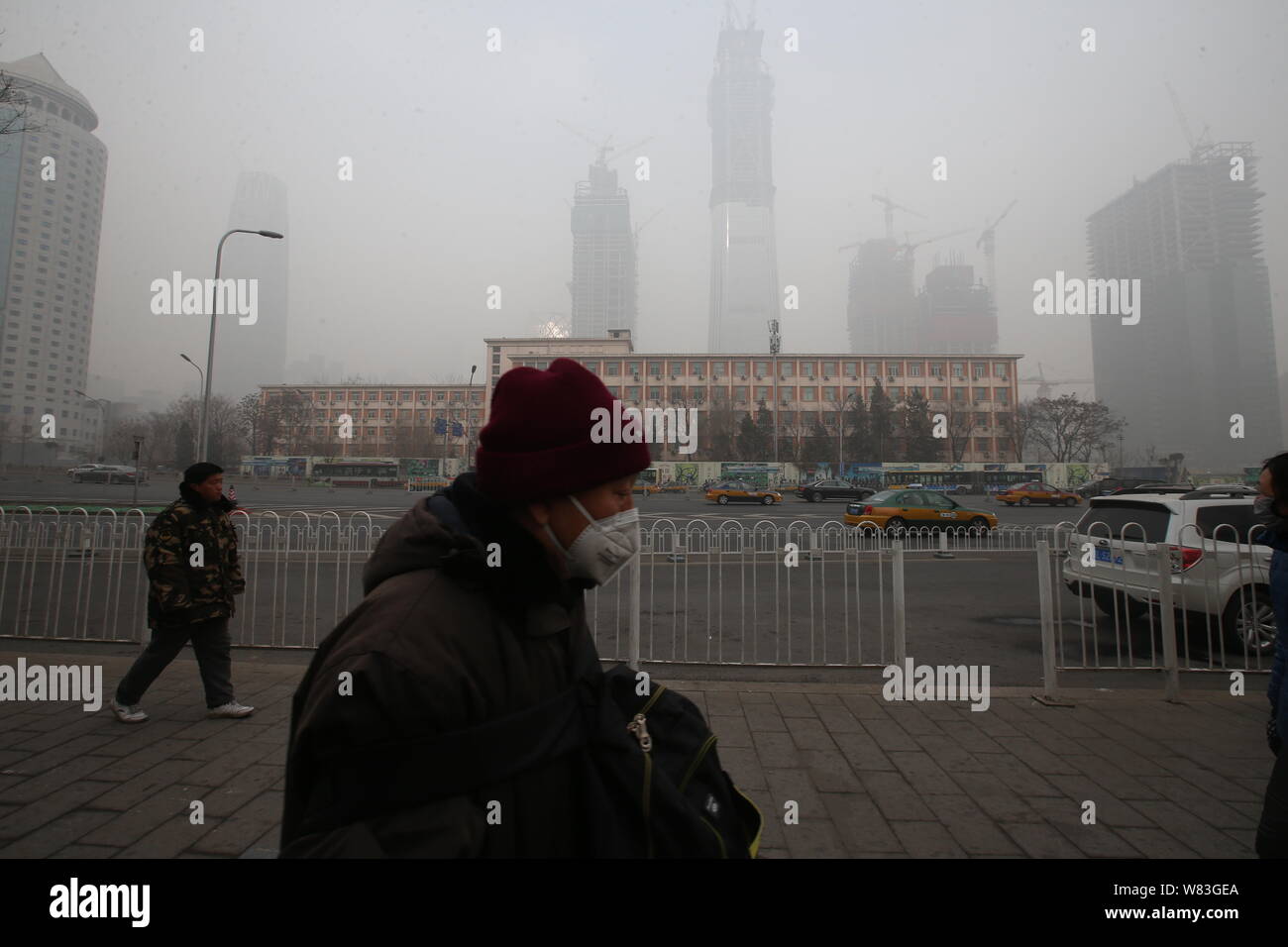Un pedone che indossa una maschera facciale contro l' inquinamento atmosferico passeggiate sulla strada di smog pesante a Pechino in Cina, 20 dicembre 2016. Cina settentrionale è stata shr Foto Stock